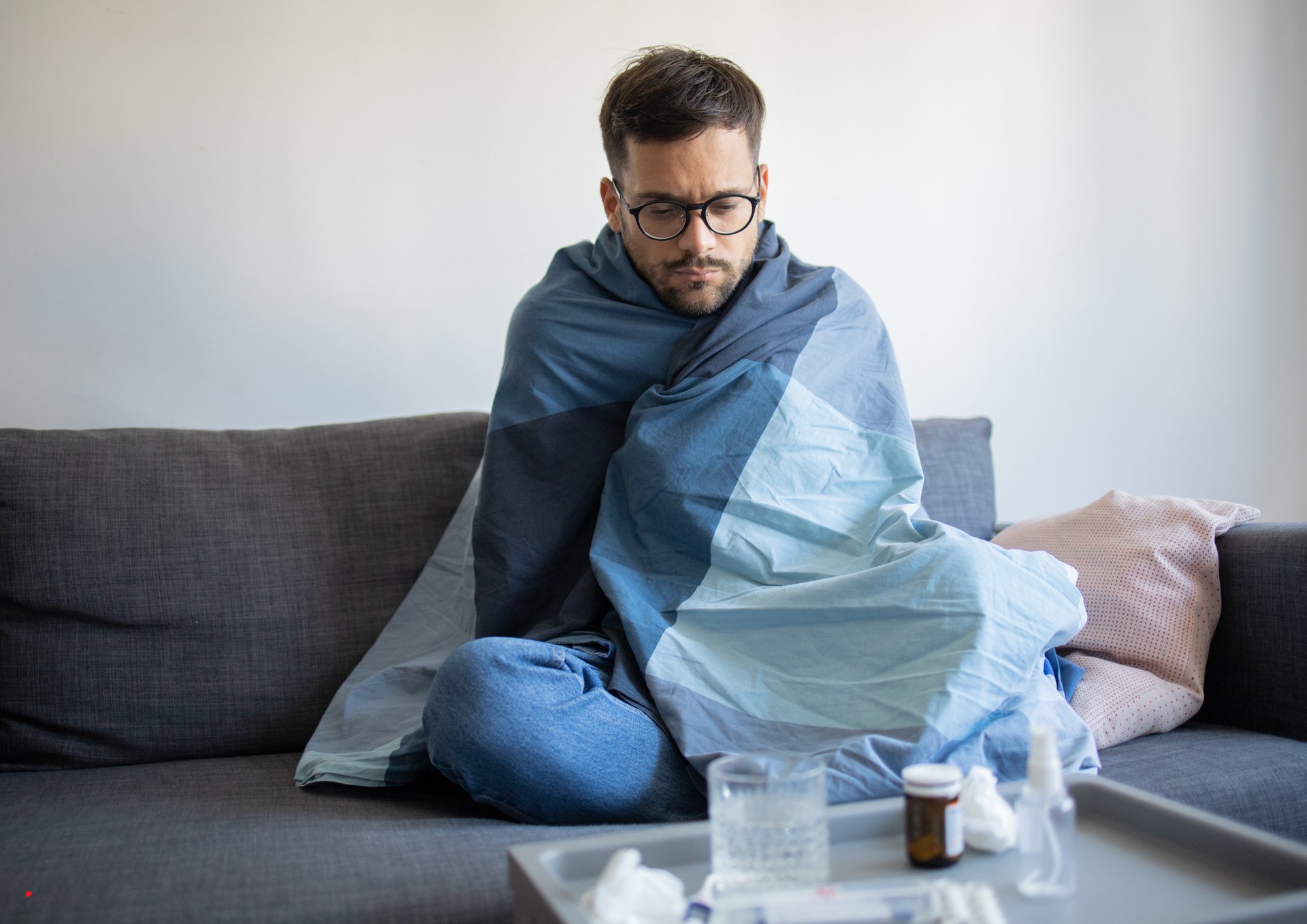 a man sitting on a couch with a blanket on it