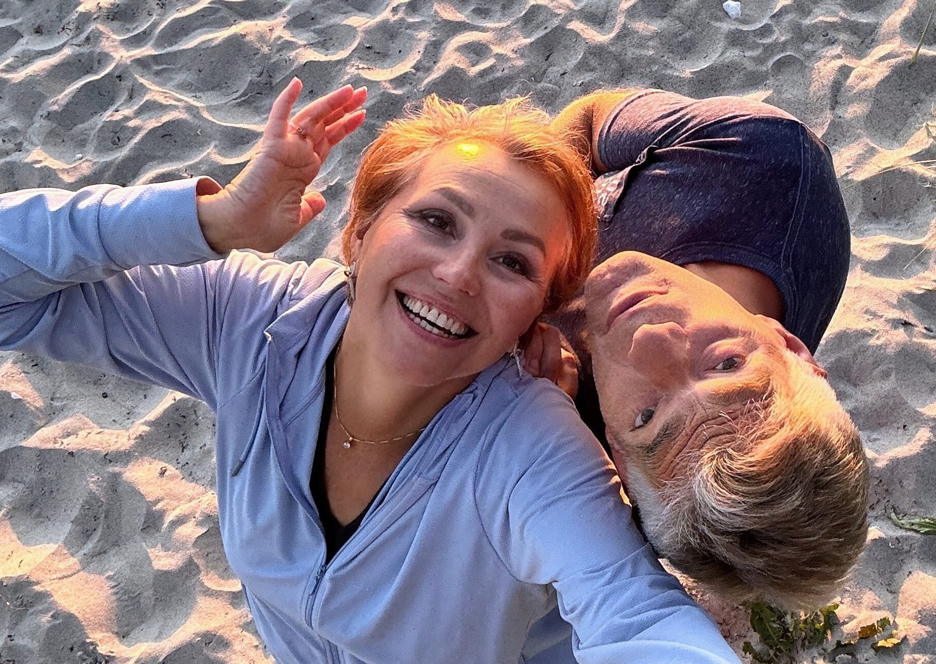 Smiling couple enjoying sunset on the beach, radiating joy, love, and playful connection.
