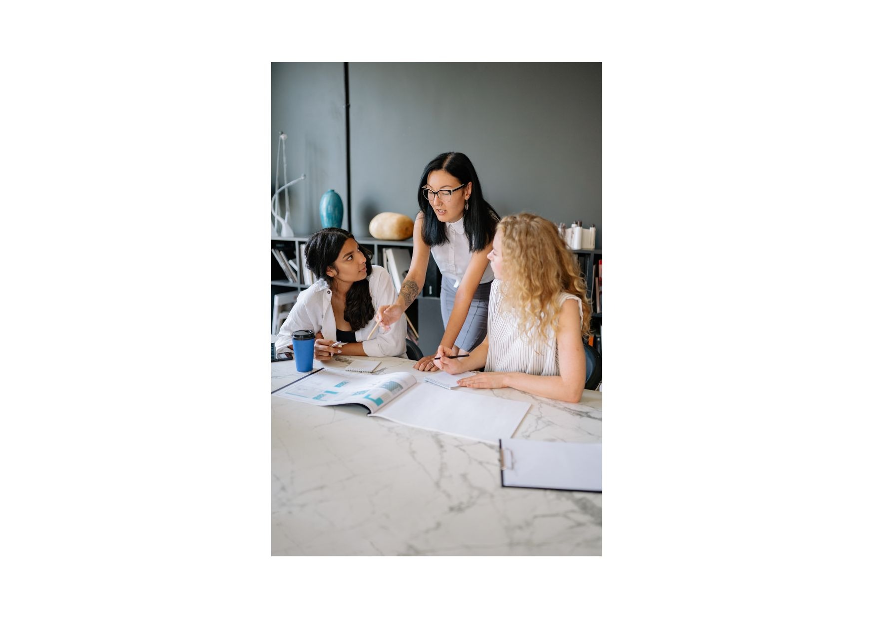 Diverse team of female colleagues collaborating on project details in a modern office.