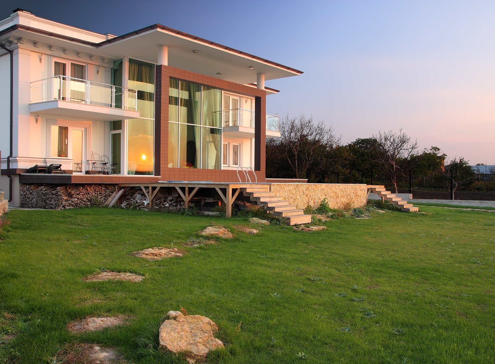 Nowoczesny dom jednorodzinny z dużymi przeszkleniami i tarasem, zachód słońca