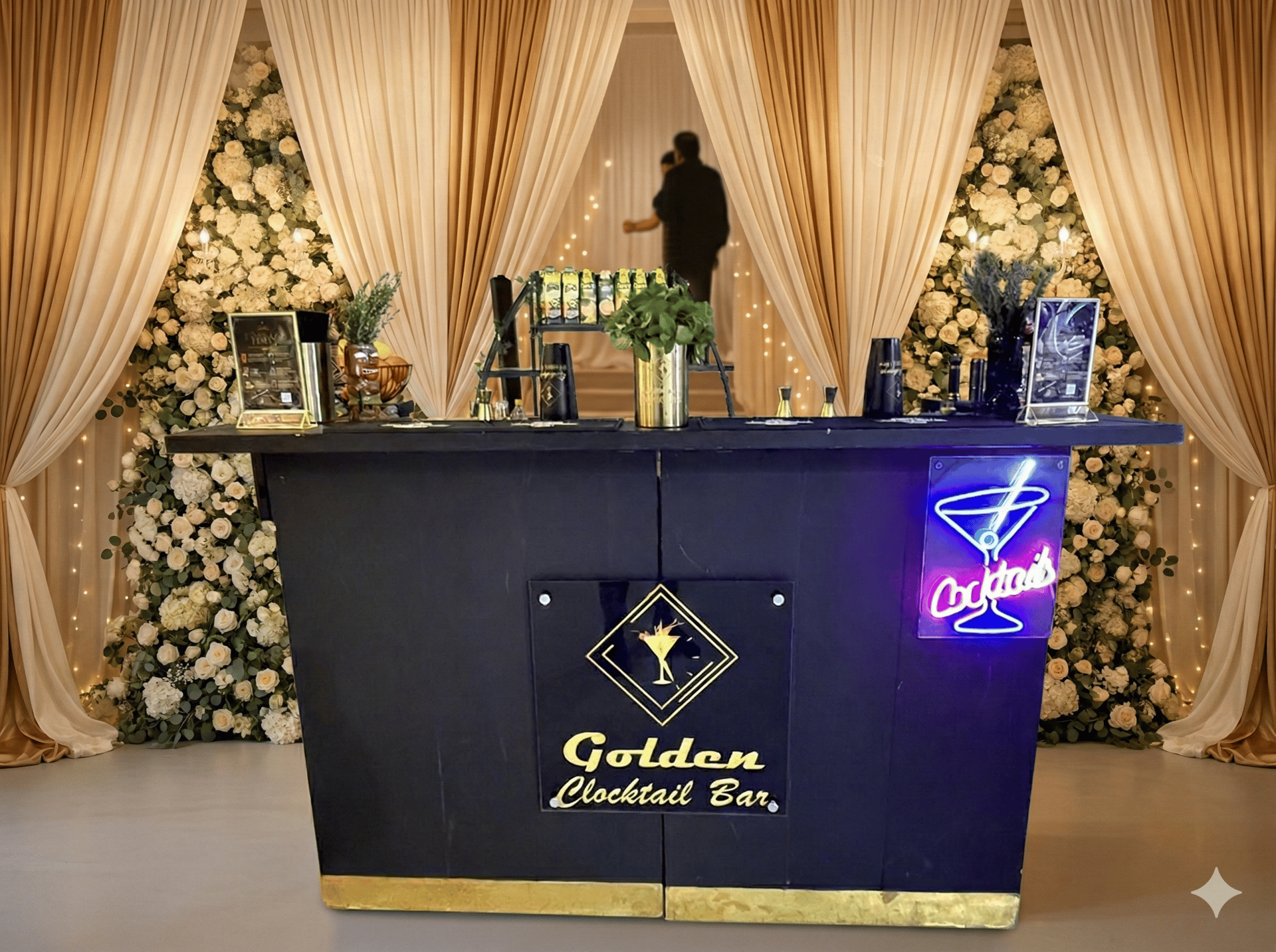 Elegant portable wedding bar with neon cocktail sign and floral backdrops for event catering.