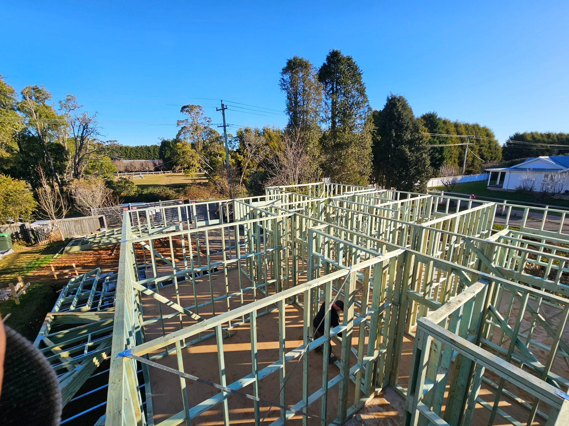 Overhead view of a new residential house construction featuring green timber wall framing.