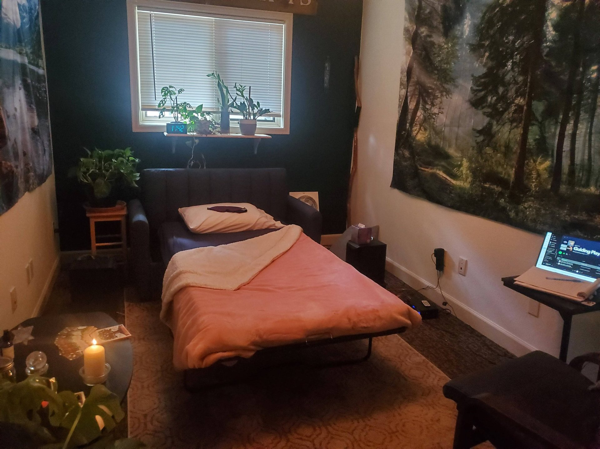 A psychedelic therapy room, set up with a bed, candles, speakers, plants and artwork