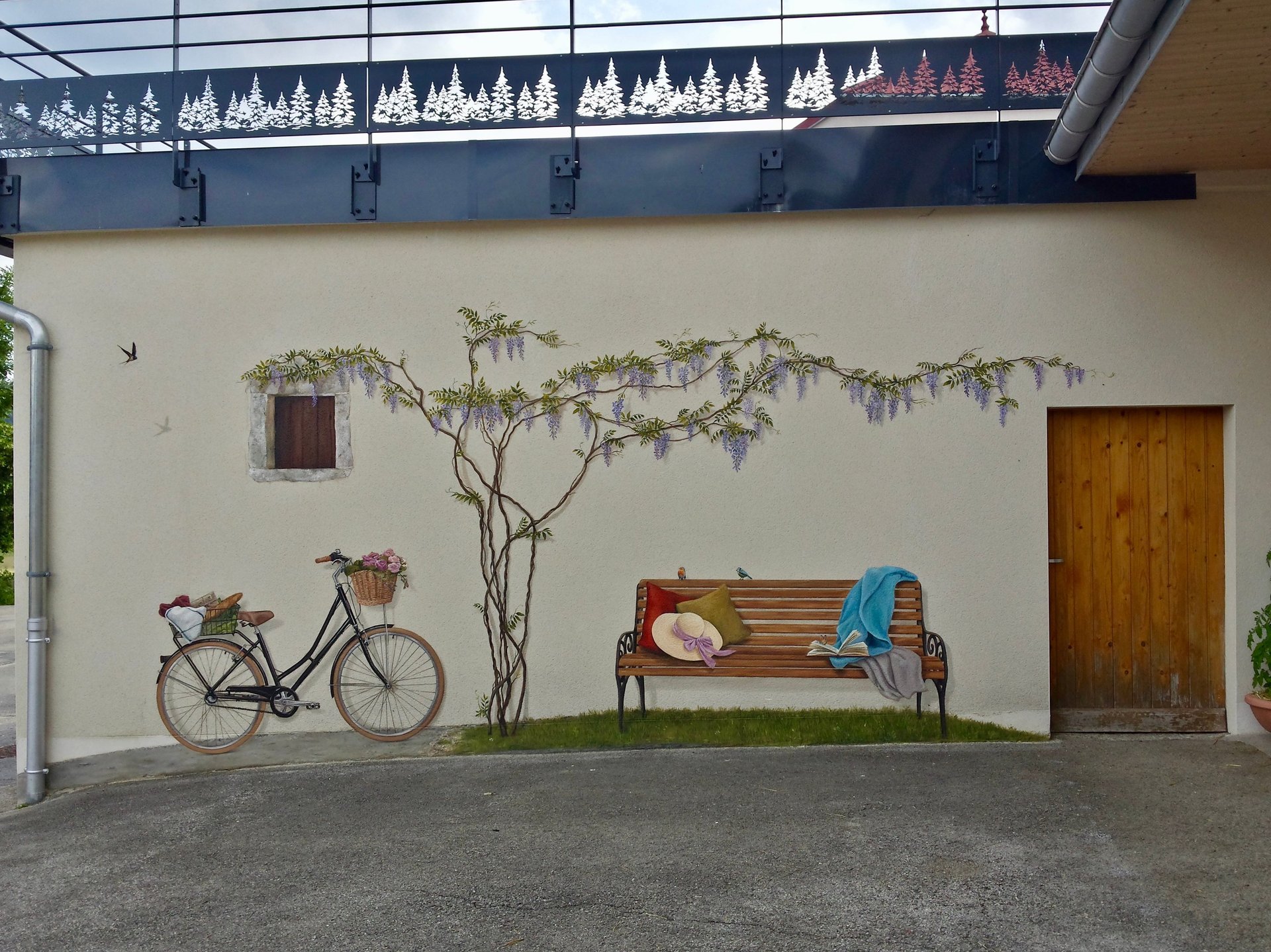 Un vélo, une glycine, un banc, des oiseaux, un livre et une fenêtre en trompe-l'oeil, ces décors peints animent une façade ex