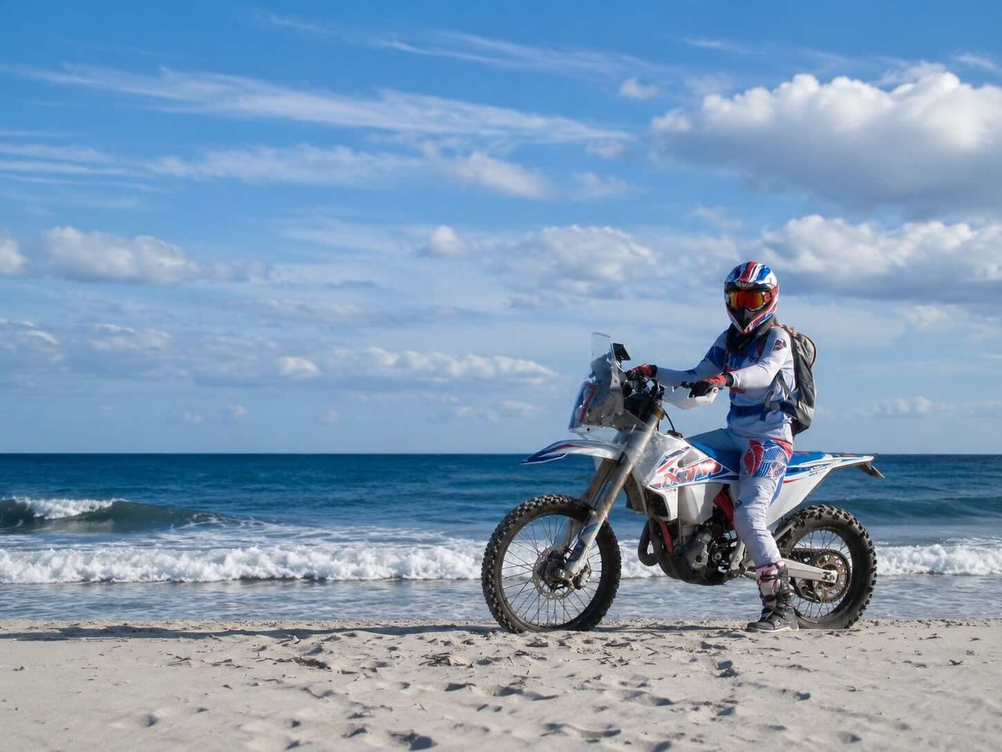 Anja auf ihrer Enduro am Strand mit dem Meer im Hintergrund
