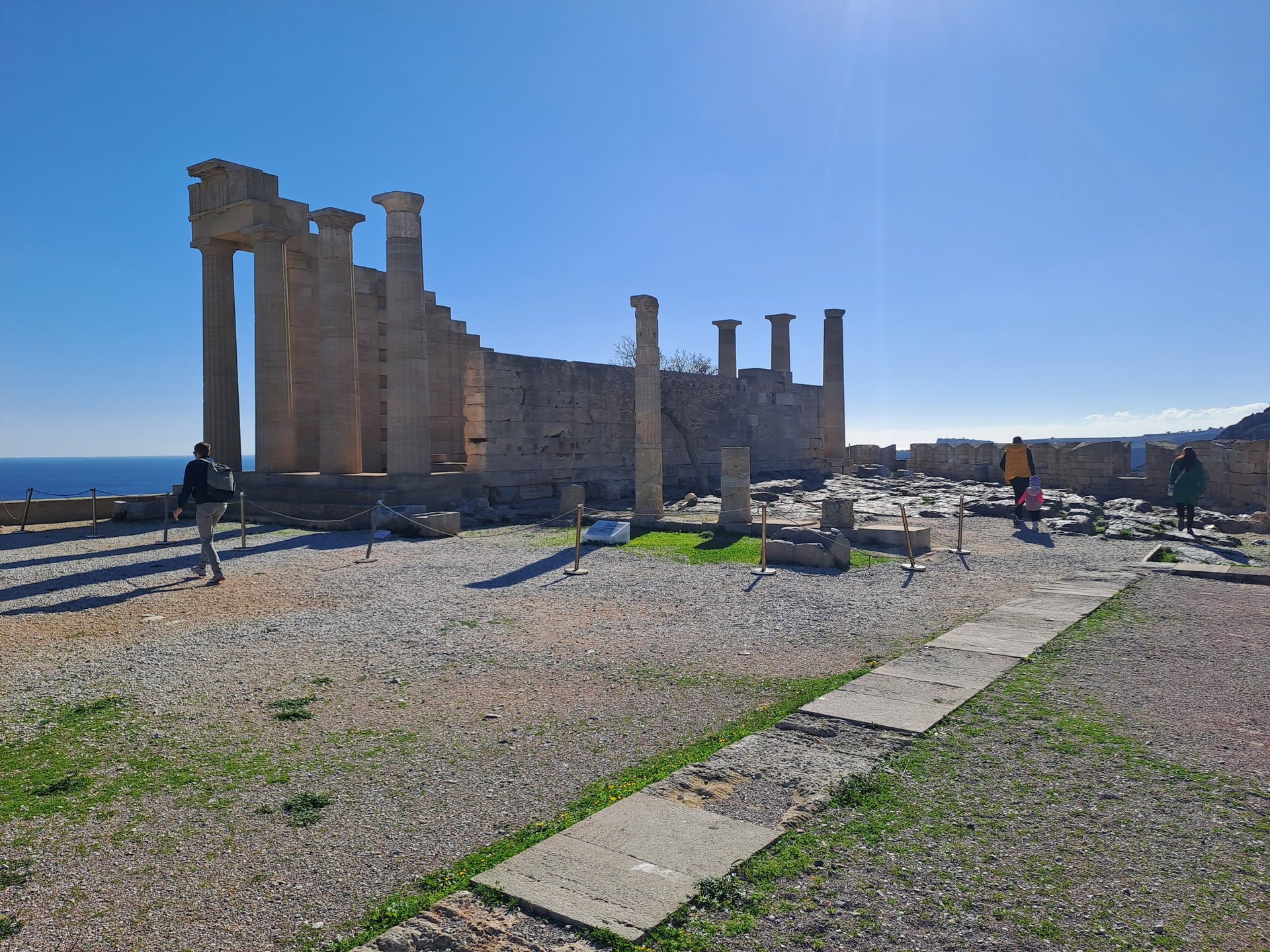 Ancient ruins of the Acropolis of Lindos in Rhodes, Greece, featuring Doric columns against a bright blue sky.