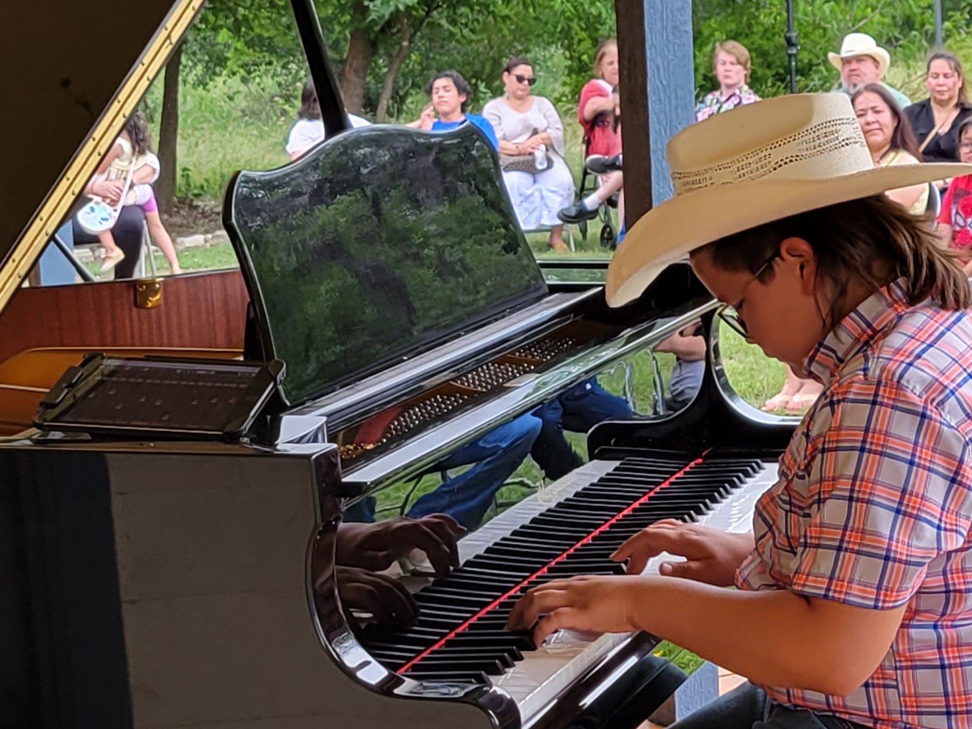 a young boy in a cowboy hat playing a piano