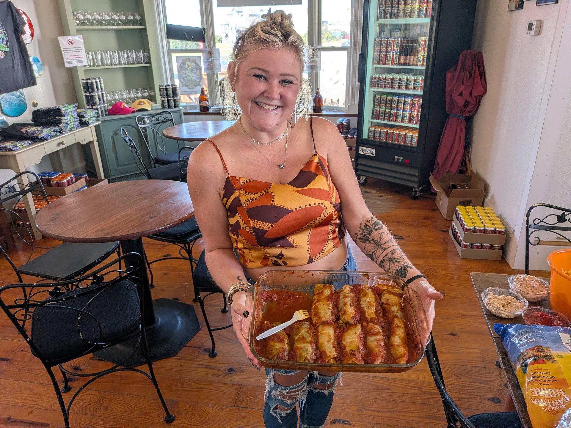 Smiling woman holding a tray of food surrounded by tables and chairs