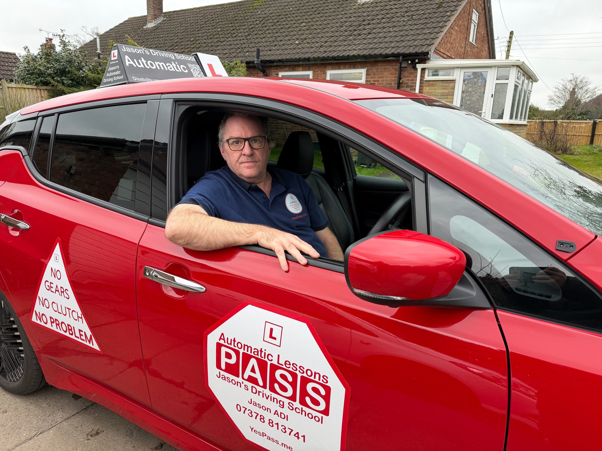 Professional driving instructor in a red automatic driving school car offering lessons for learner drivers.