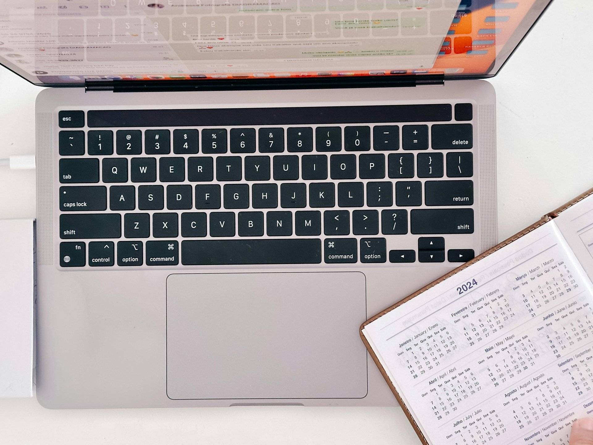 An open calendar planner, slightly laid over the keyboard of an open laptop.