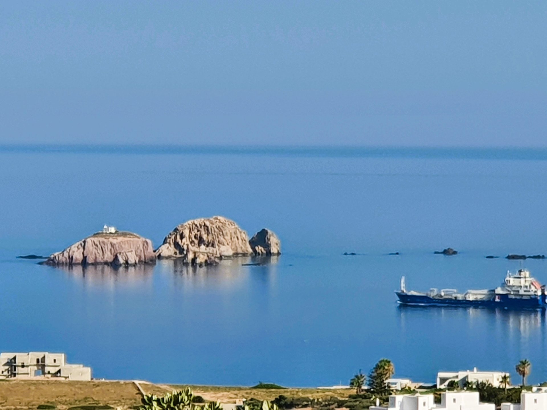 Sea scape of Paros looking to the sea, small rocky islands and a comertial vesel