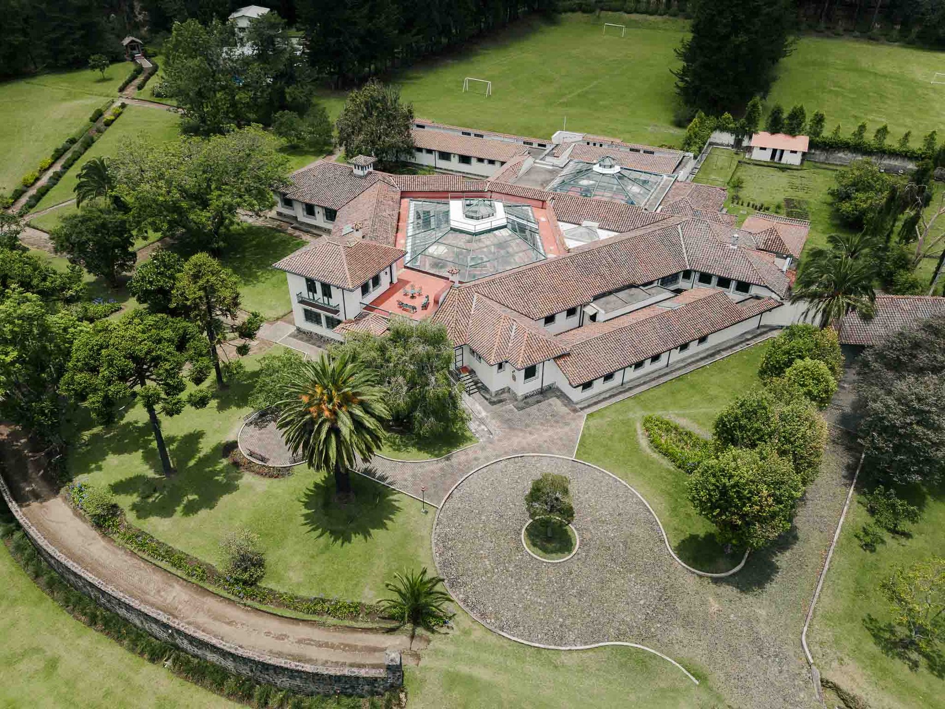 Fotografía con dron de mansión colonial de paredes blancas con techo naranja, cúpulas rodeada de naturaleza Quito Ecuador