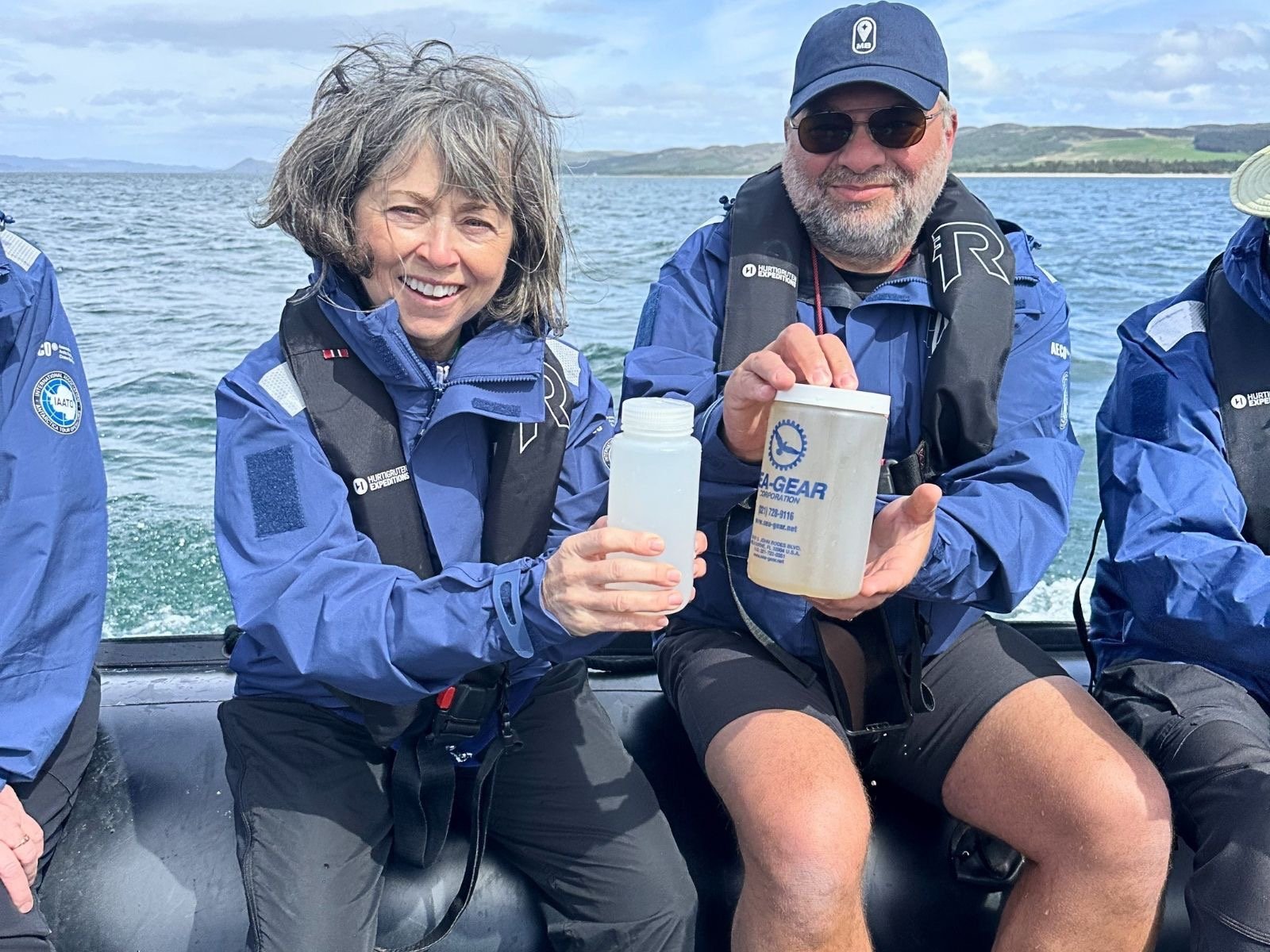 Two researchers on a boat collect ocean water samples for marine conservation research.