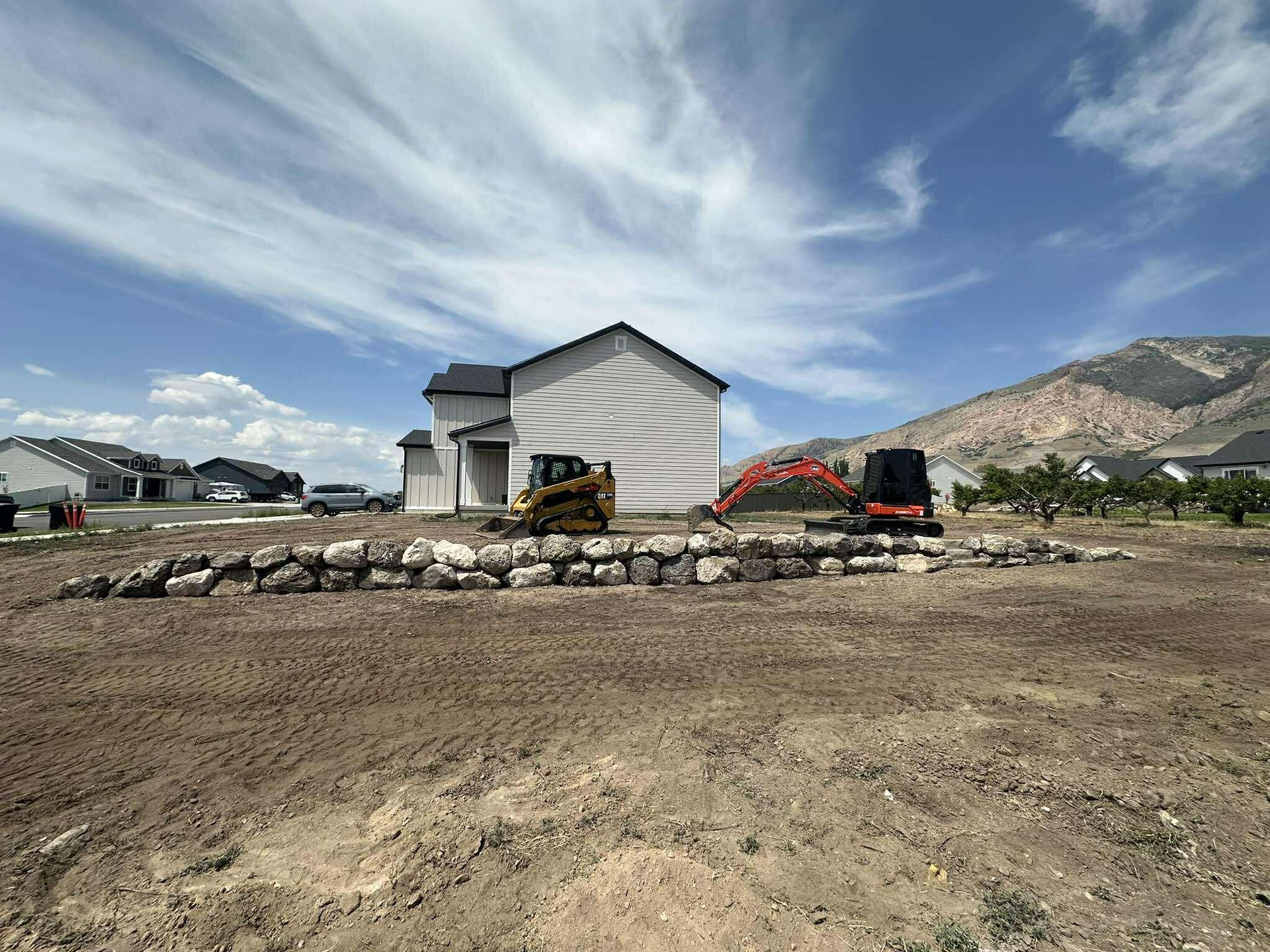 Boulder retaining wall with skid steer and mini excavator sitting idle