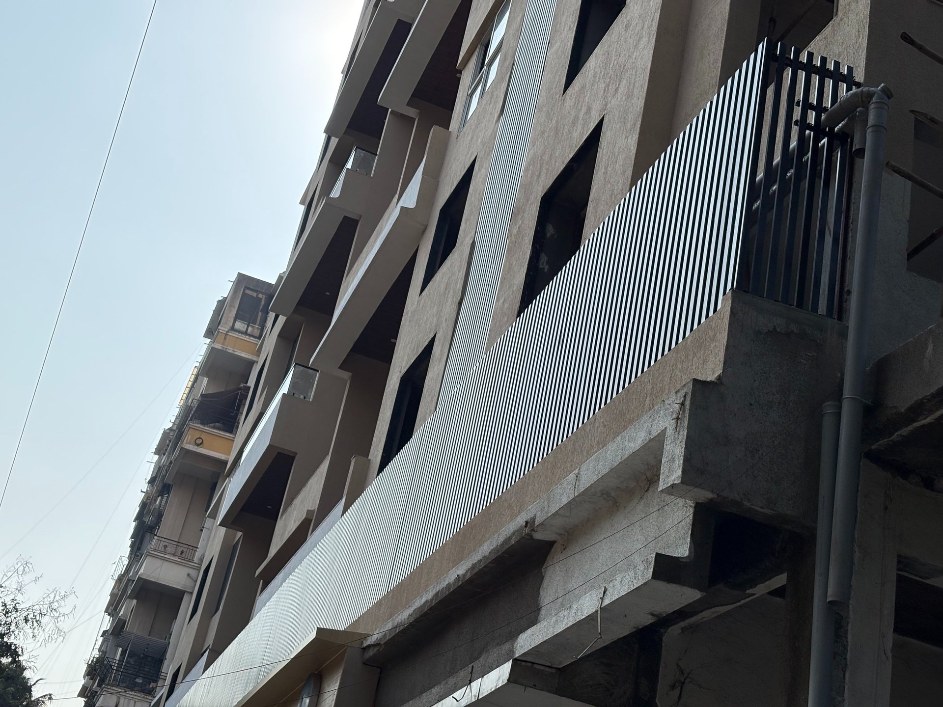 Low angle view of a modern apartment building under construction with metal balcony louvers.