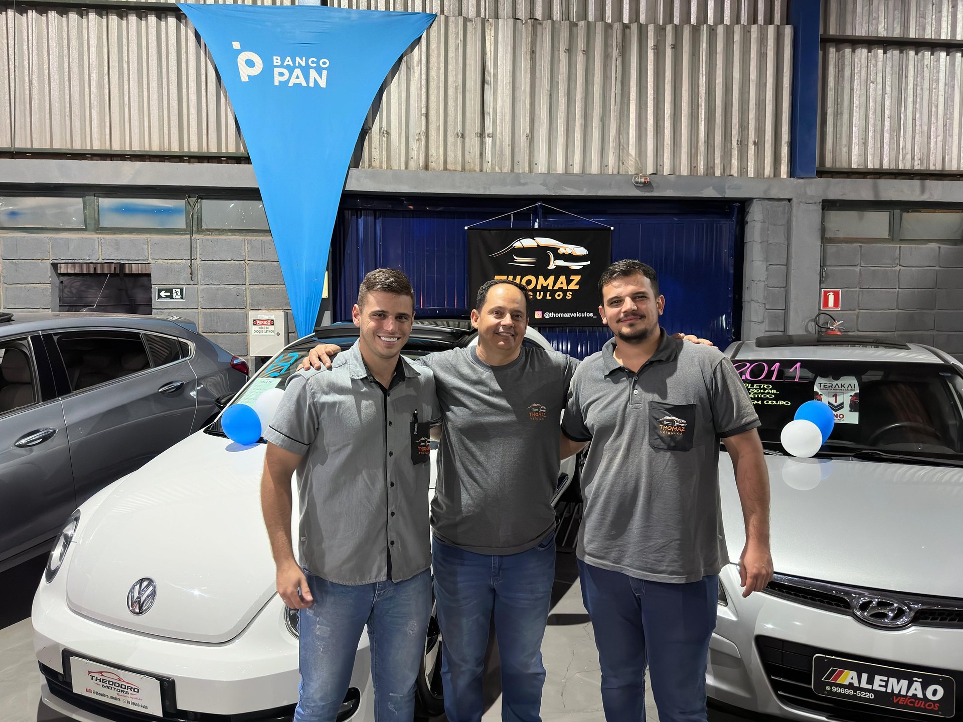 two men standing next to each other in front of a car