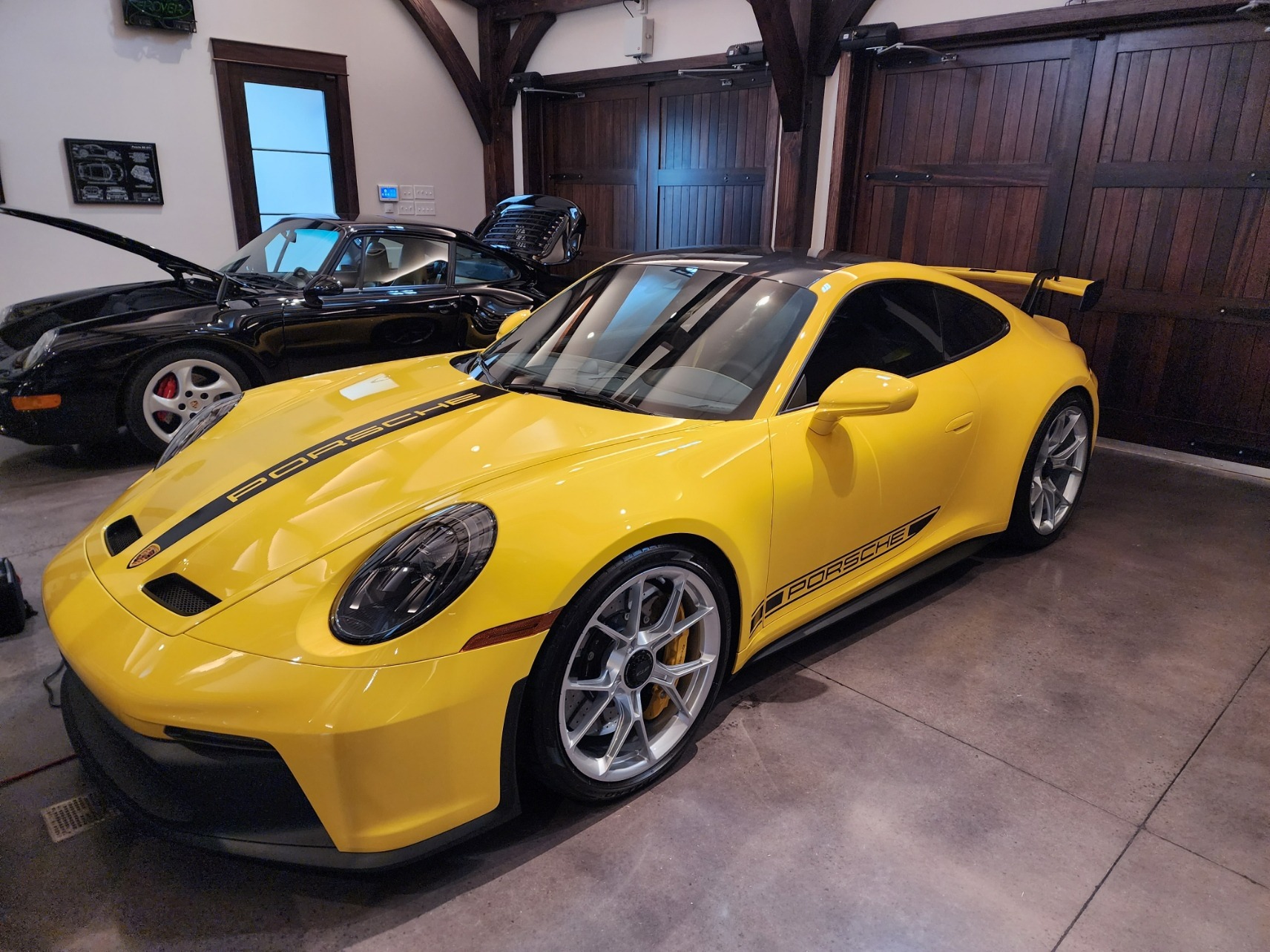 a yellow Porsche 911 GT3 parked in a garage next to a 1989 Porsche 911 Carrera awaiting appraisal
