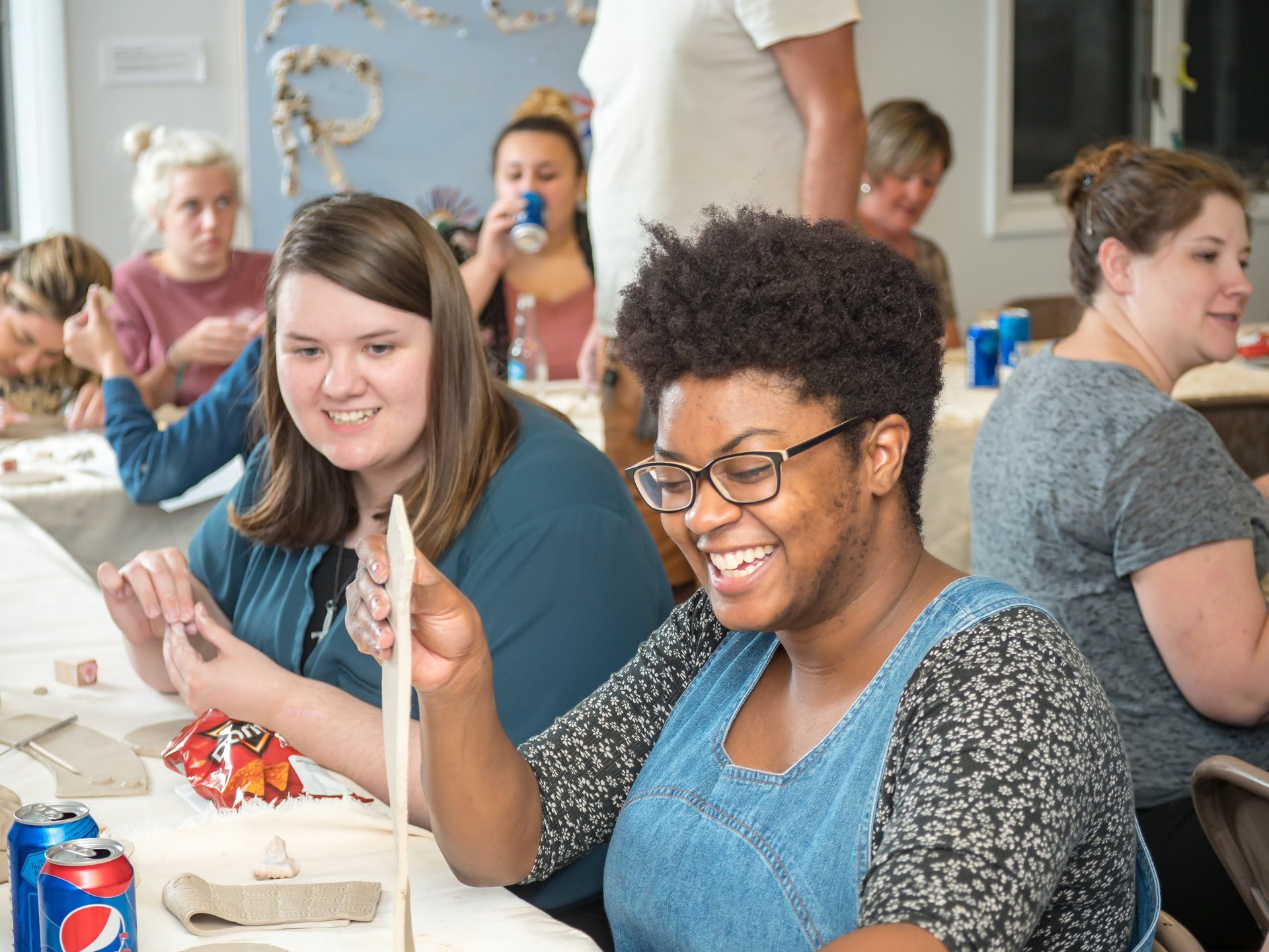 Individuals at a private party laughing as they begin their clay project.