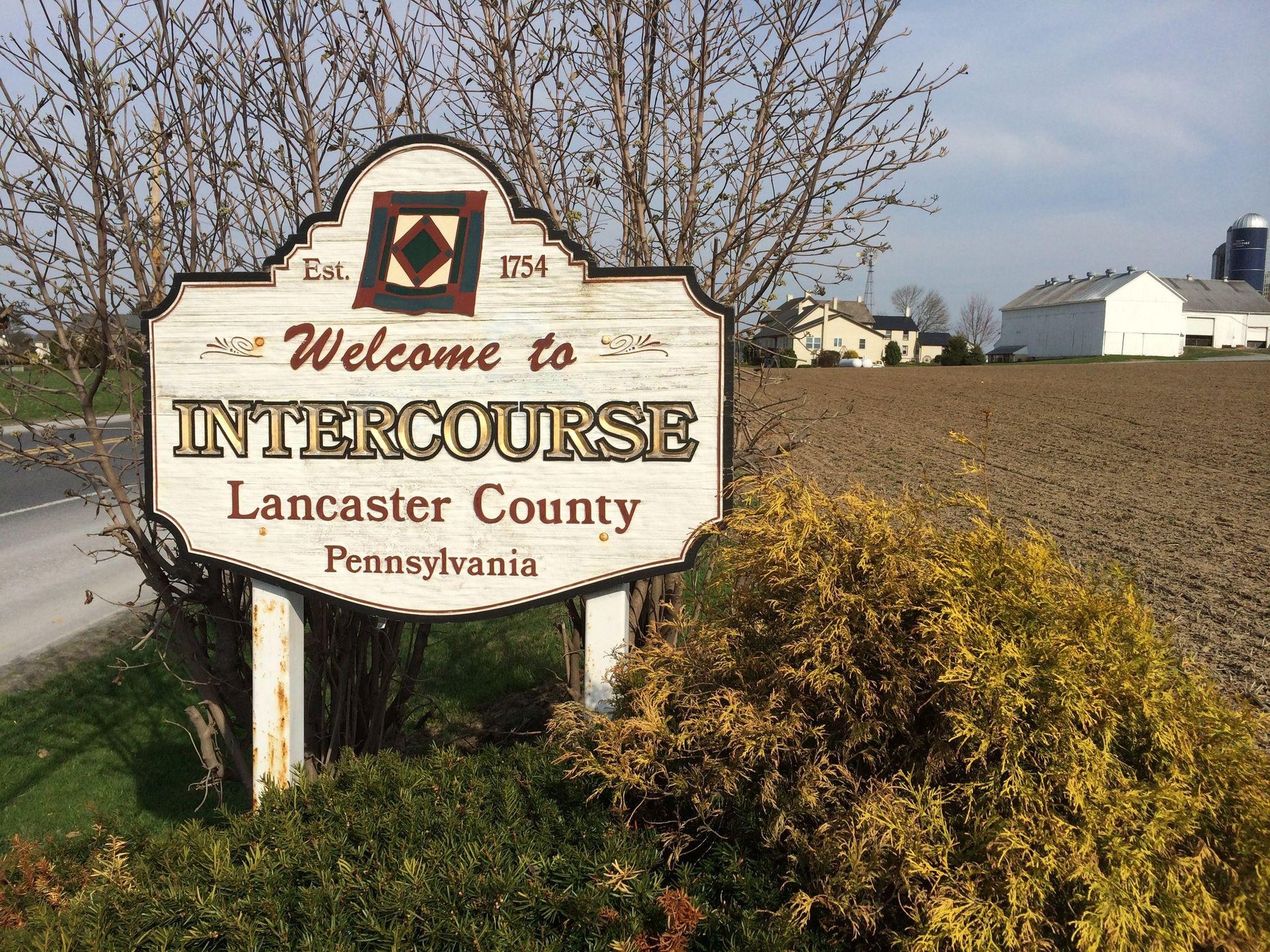 Welcome to Intercourse Lancaster County Pennsylvania road sign near Amish farm country fields.