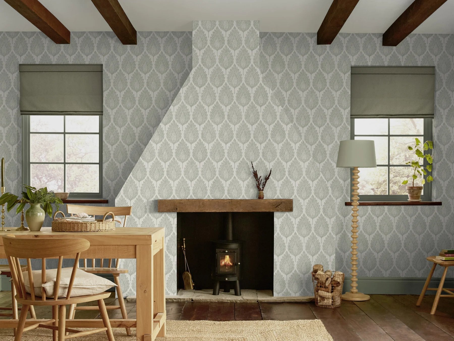 Rustic living room featuring grey leaf patterned wallpaper, a wood burning stove, and exposed ceiling beams.