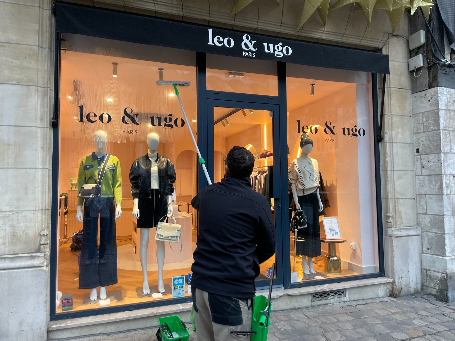 Technicien de M & M Services Pro nettoyant la vitrine de la boutique Léo et Ugo à Rouen avec une rac