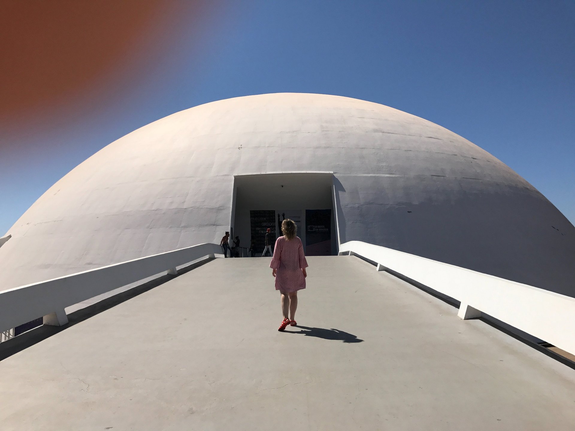 a woman in a pink dress walking down a walkway