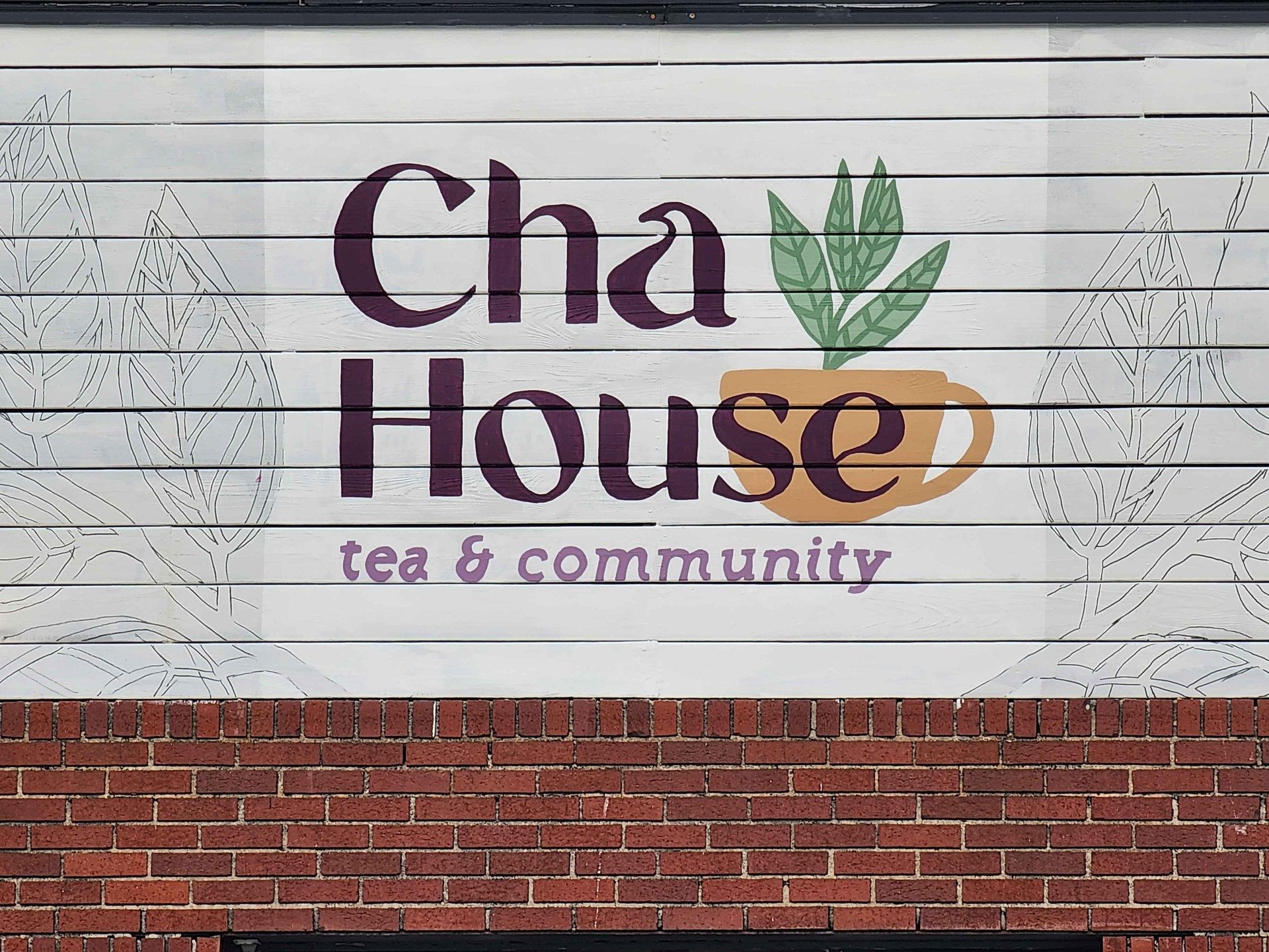 Cha House tea & community mural painted on a white wood wall.
