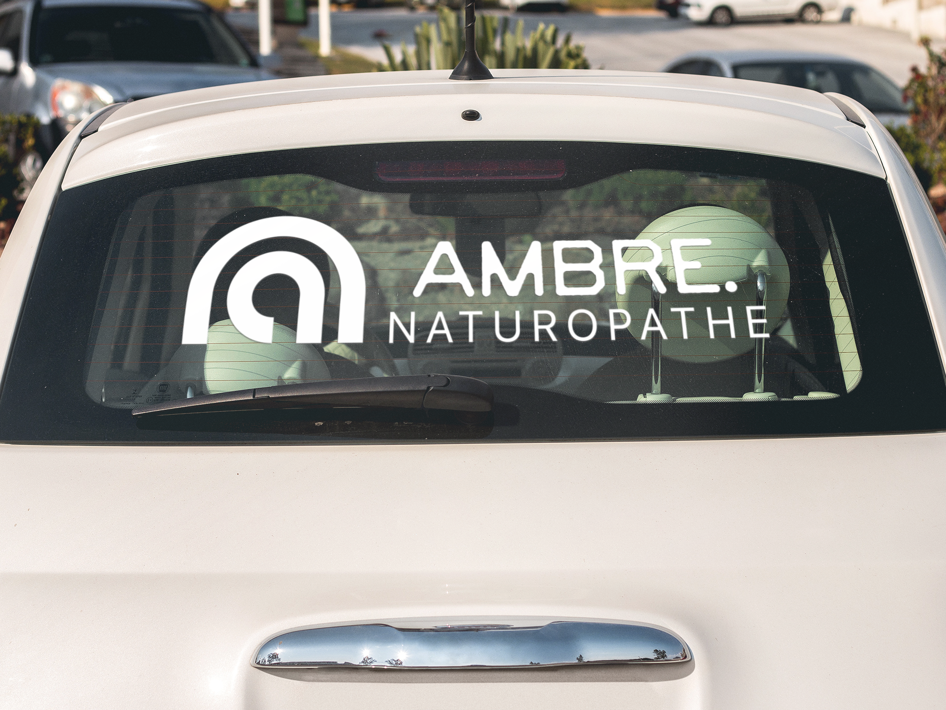 Décalcomanie blanc sur vitre arrière de voiture d'une naturopathe avec un logo professionnel.