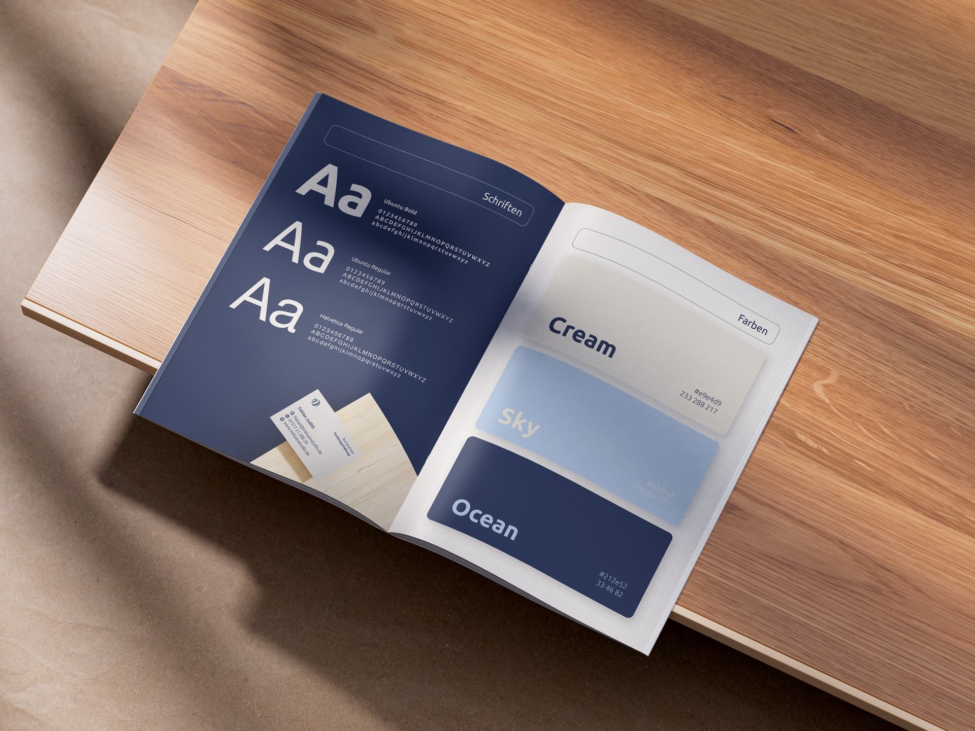 Aufgeklappte Broschüre in inklusivstudio-Farben auf Holzplatte