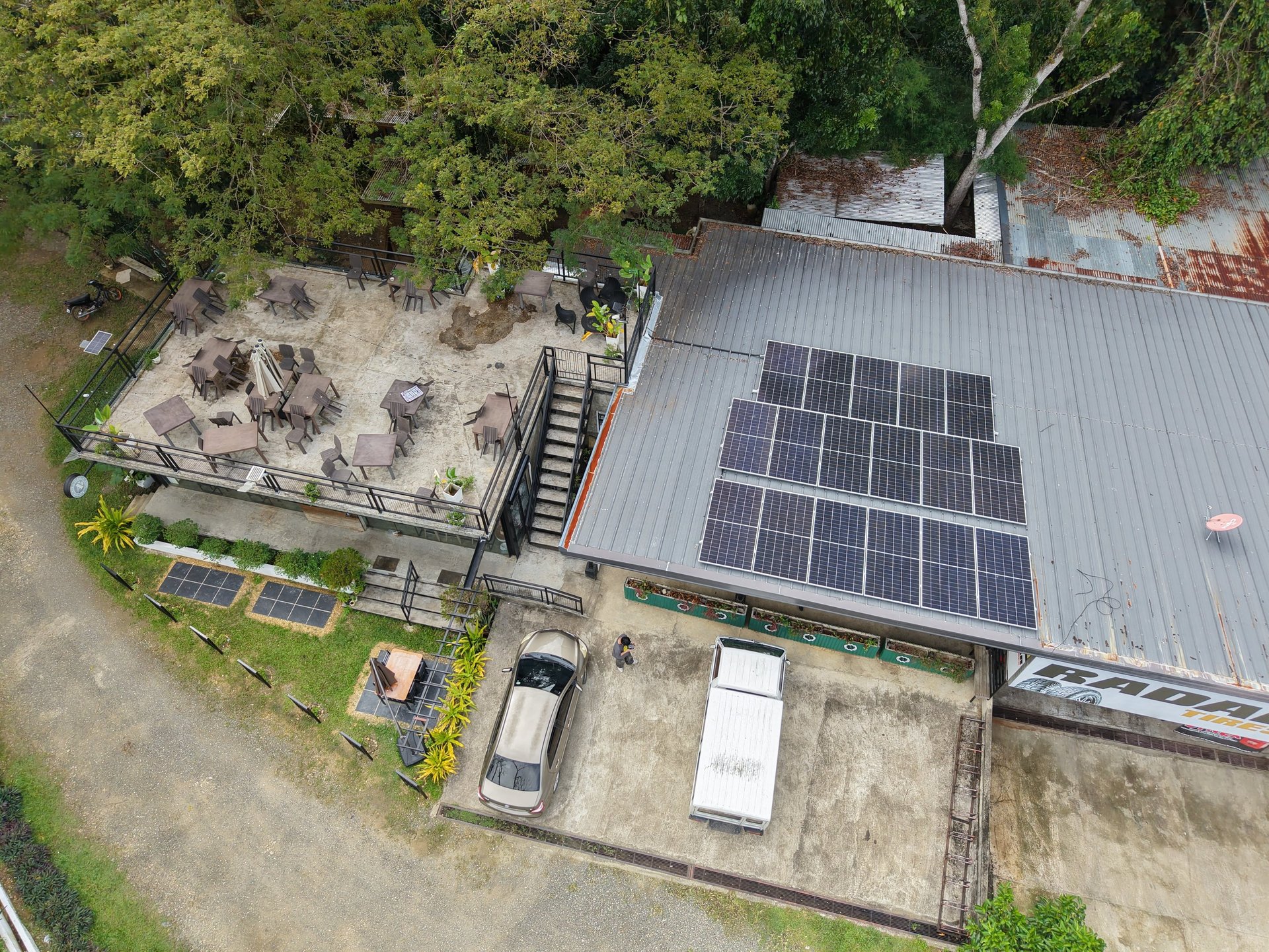 Aerial view of a restaurant with solar panels on the roof and an outdoor patio dining area.