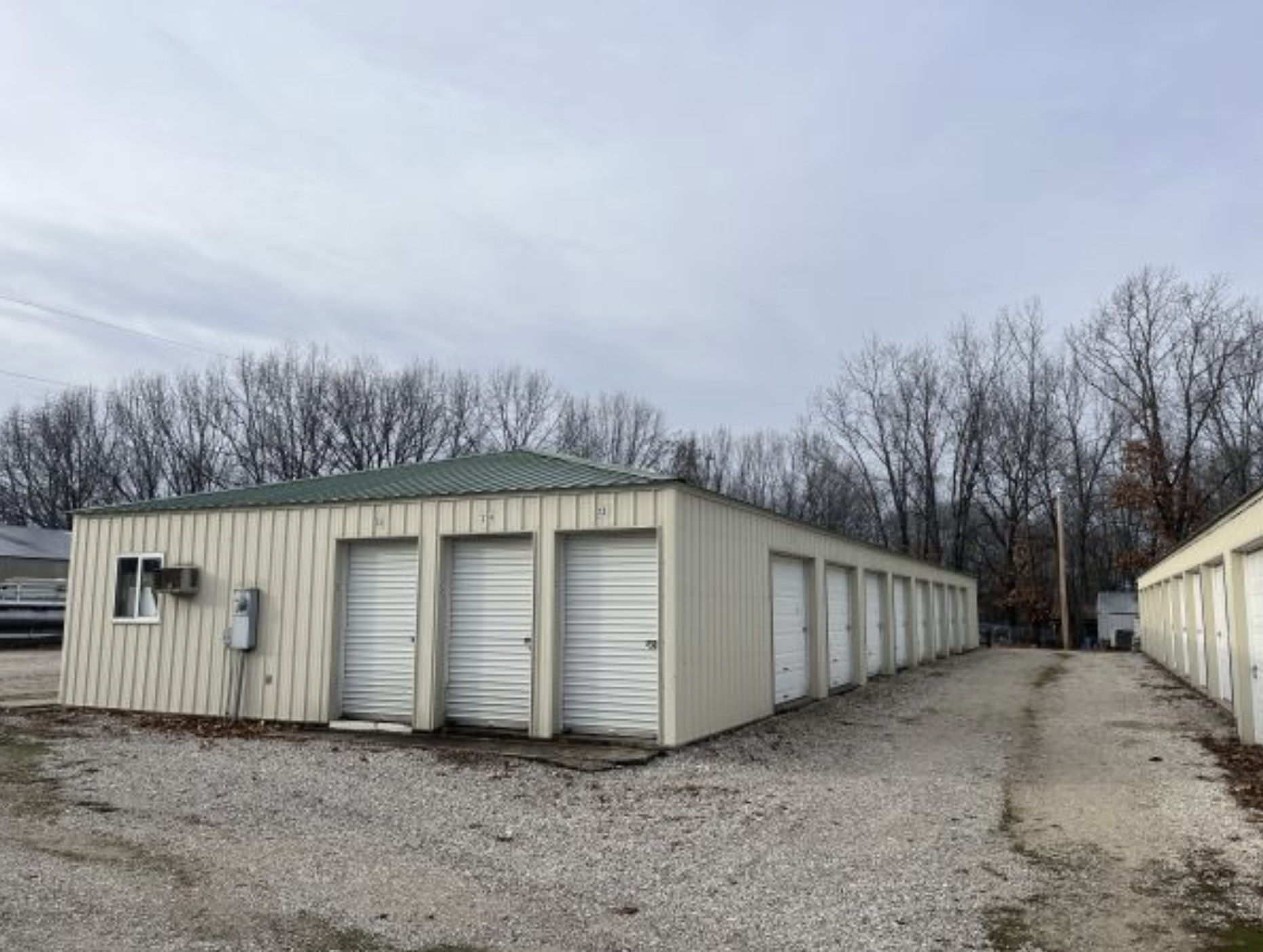 Row of outdoor metal self-storage units with white roll-up doors and gravel driveway. Alberta