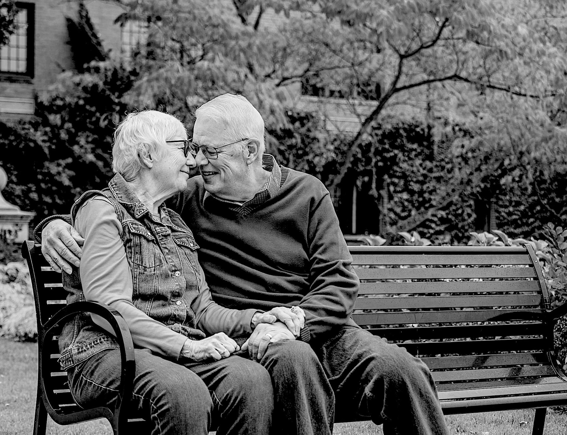 couple de personnes âgées se tenant la main, assis sur un banc