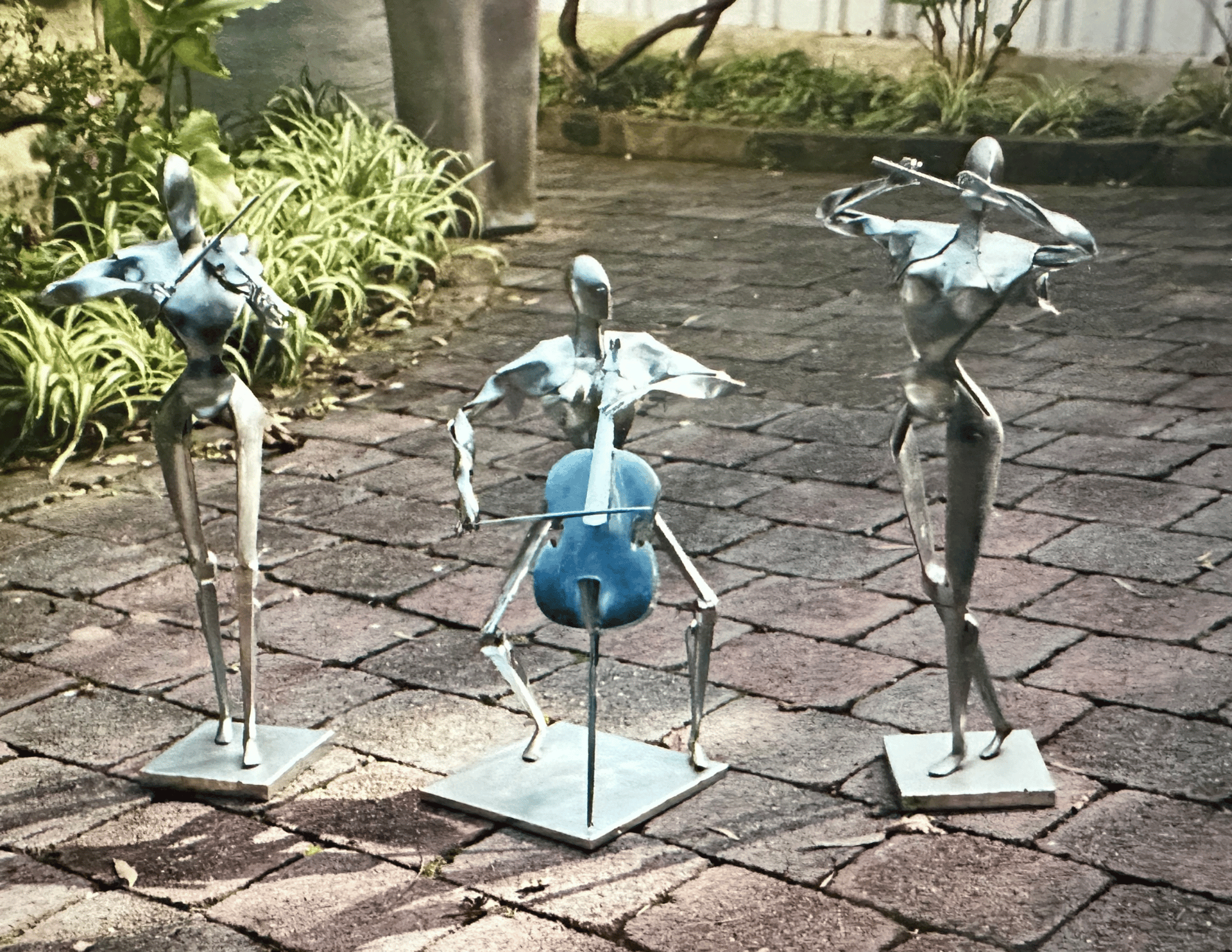 three zinc coated steel sculptures of musicians playing instruments