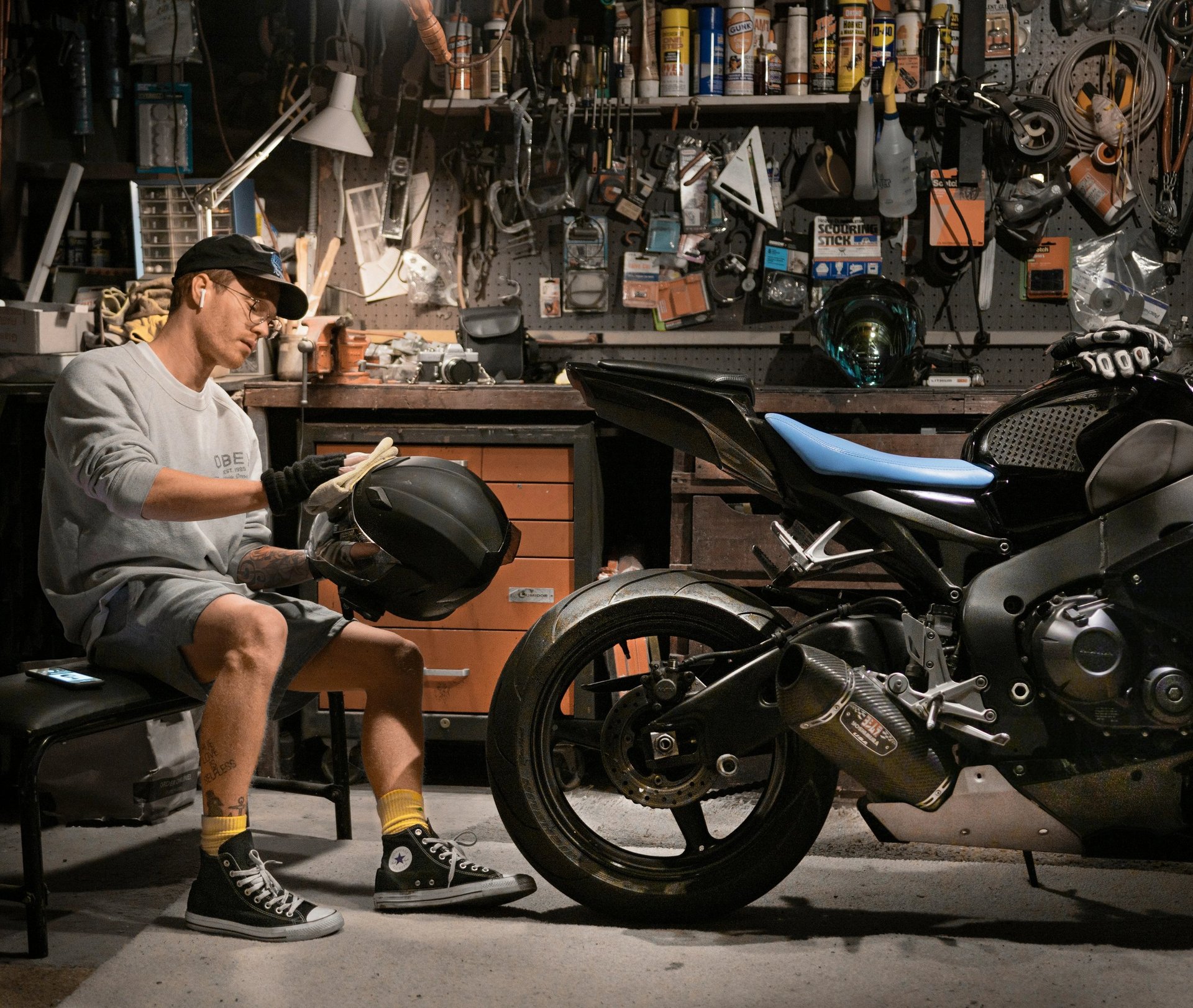 man cleaning his motorcycle helmet next to his motorcycle