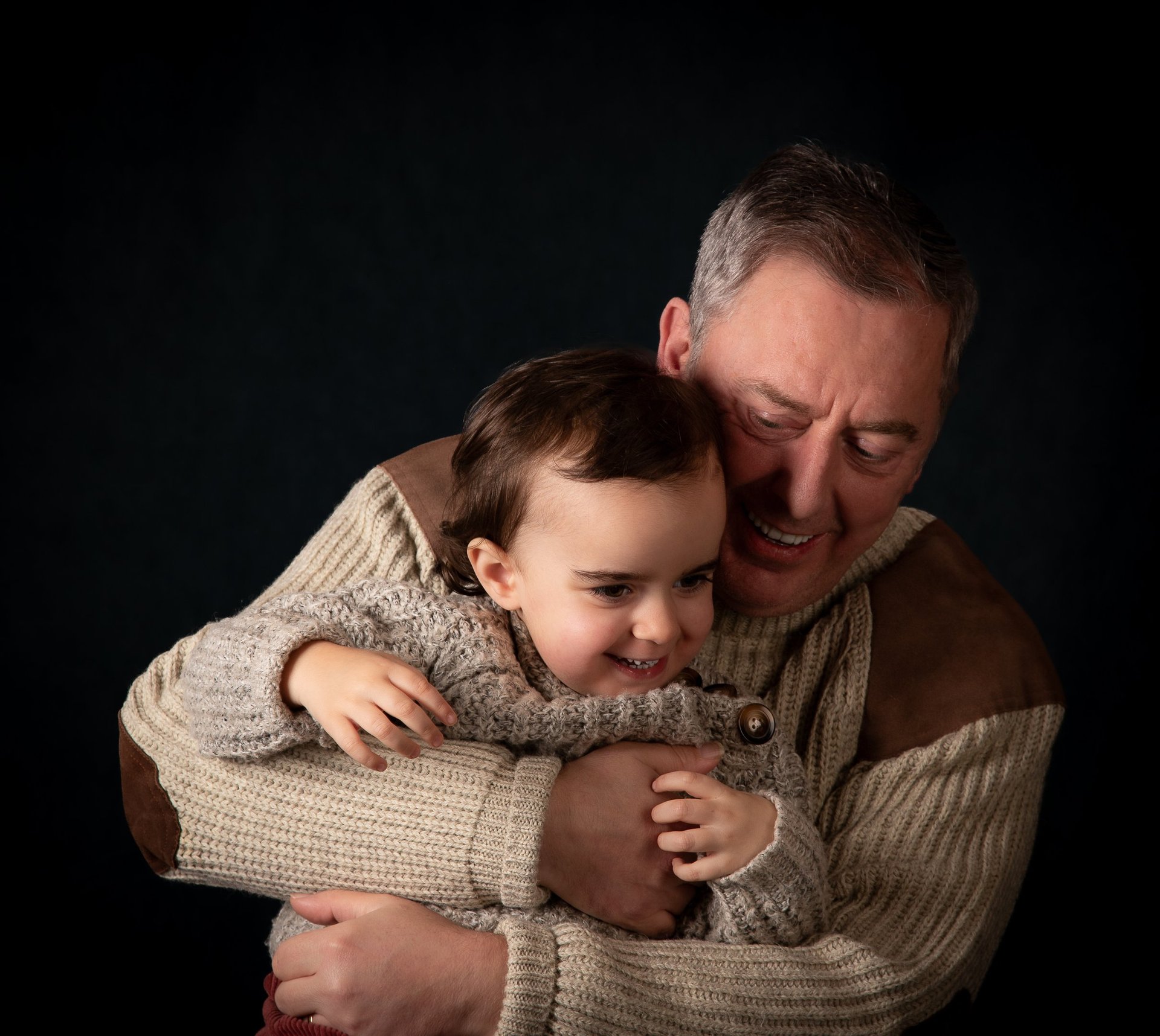 A smiling father hugs his happy young daughter in a heartwarming family portrait.