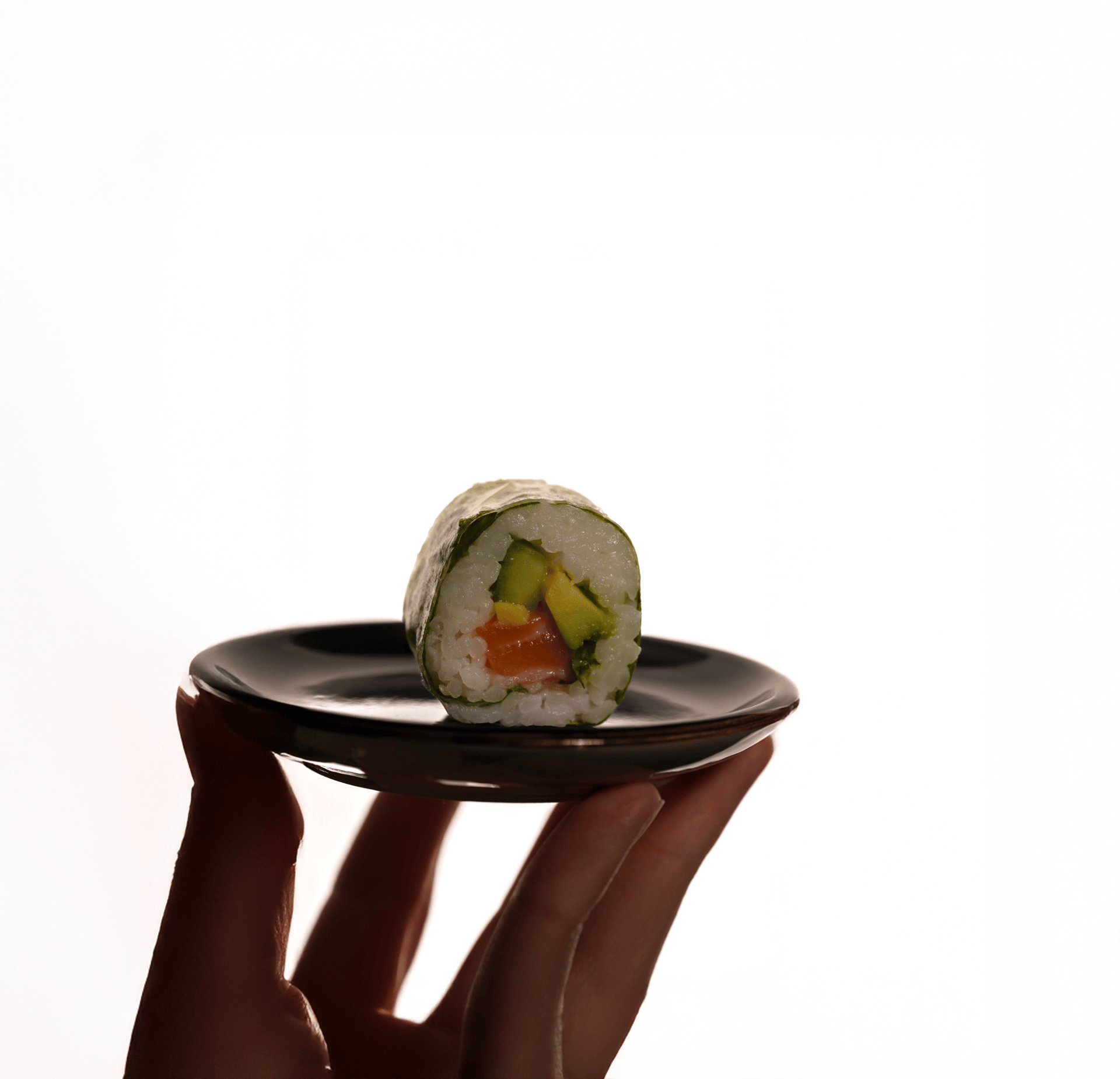 un sushi posé sur une assiette avec un fond blanc très lumineux