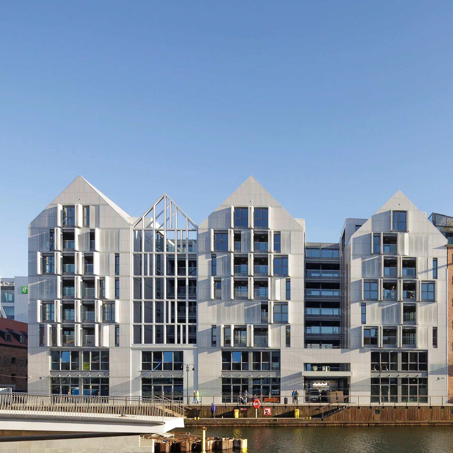 Nowoczesny budynek nad wodą z przeszkleniami i dwuspadowymi dachami