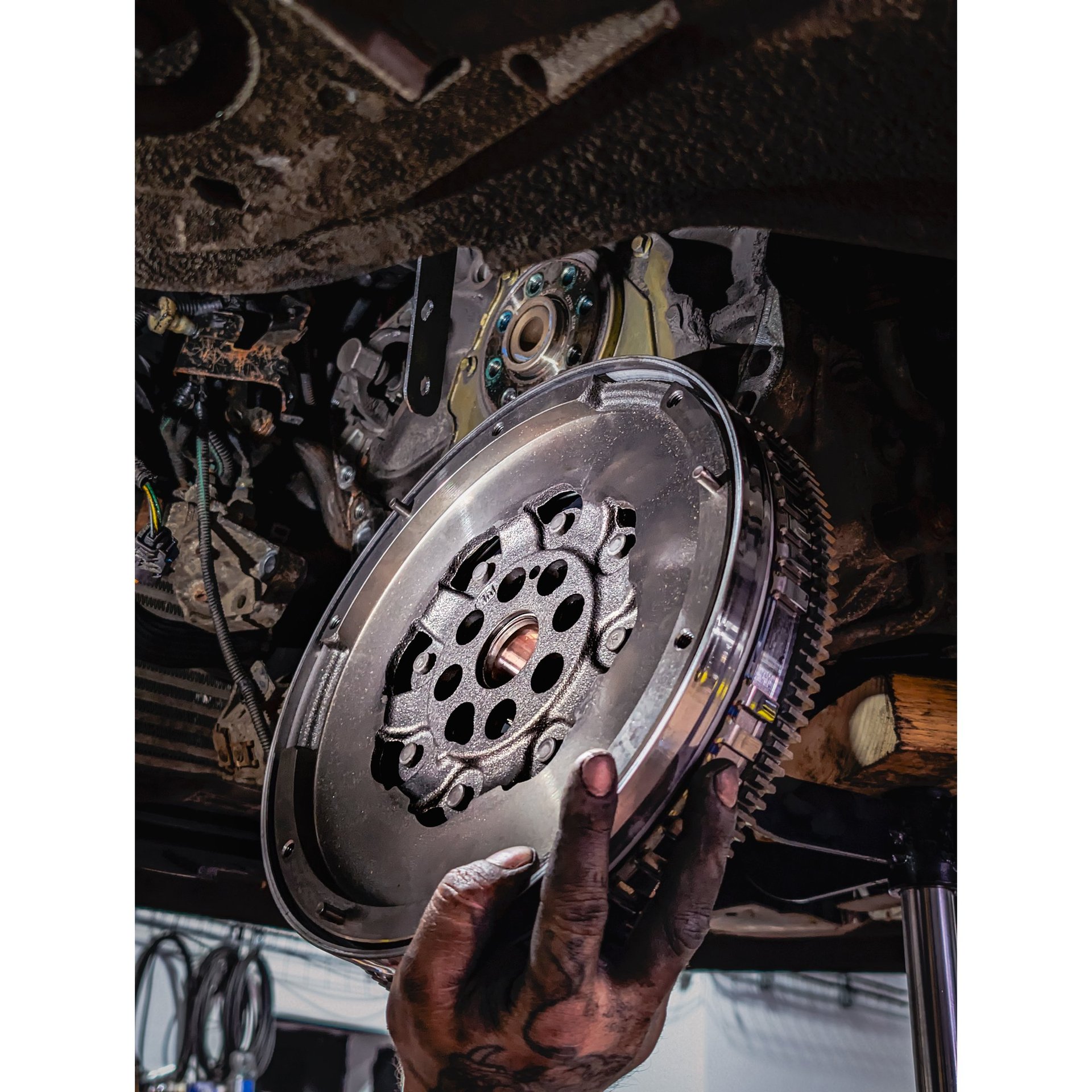 A mechanic installing a new dual-mass flywheel into a car engine during a clutch repair service.