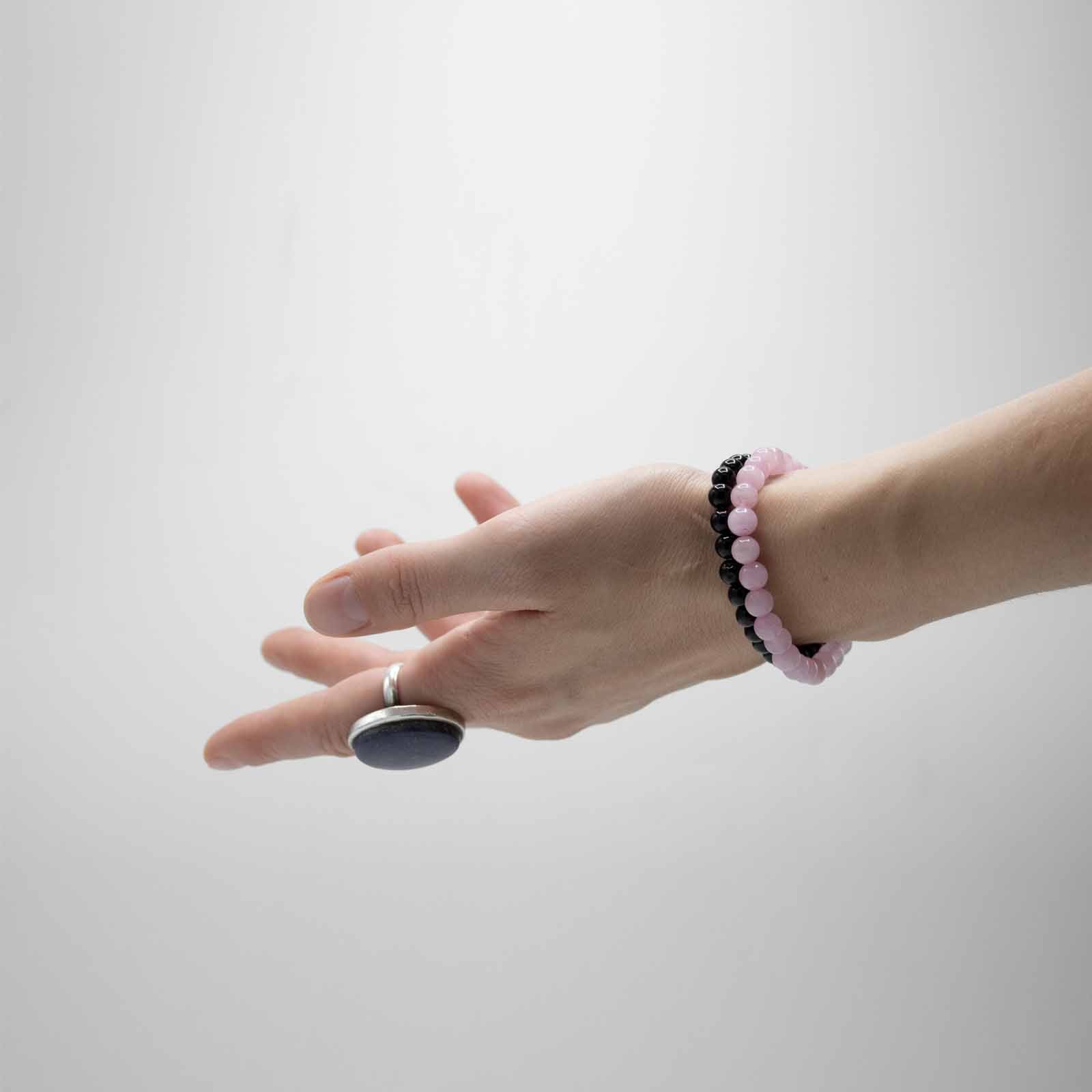 a person's hand holding a rock with a beaded bracelet