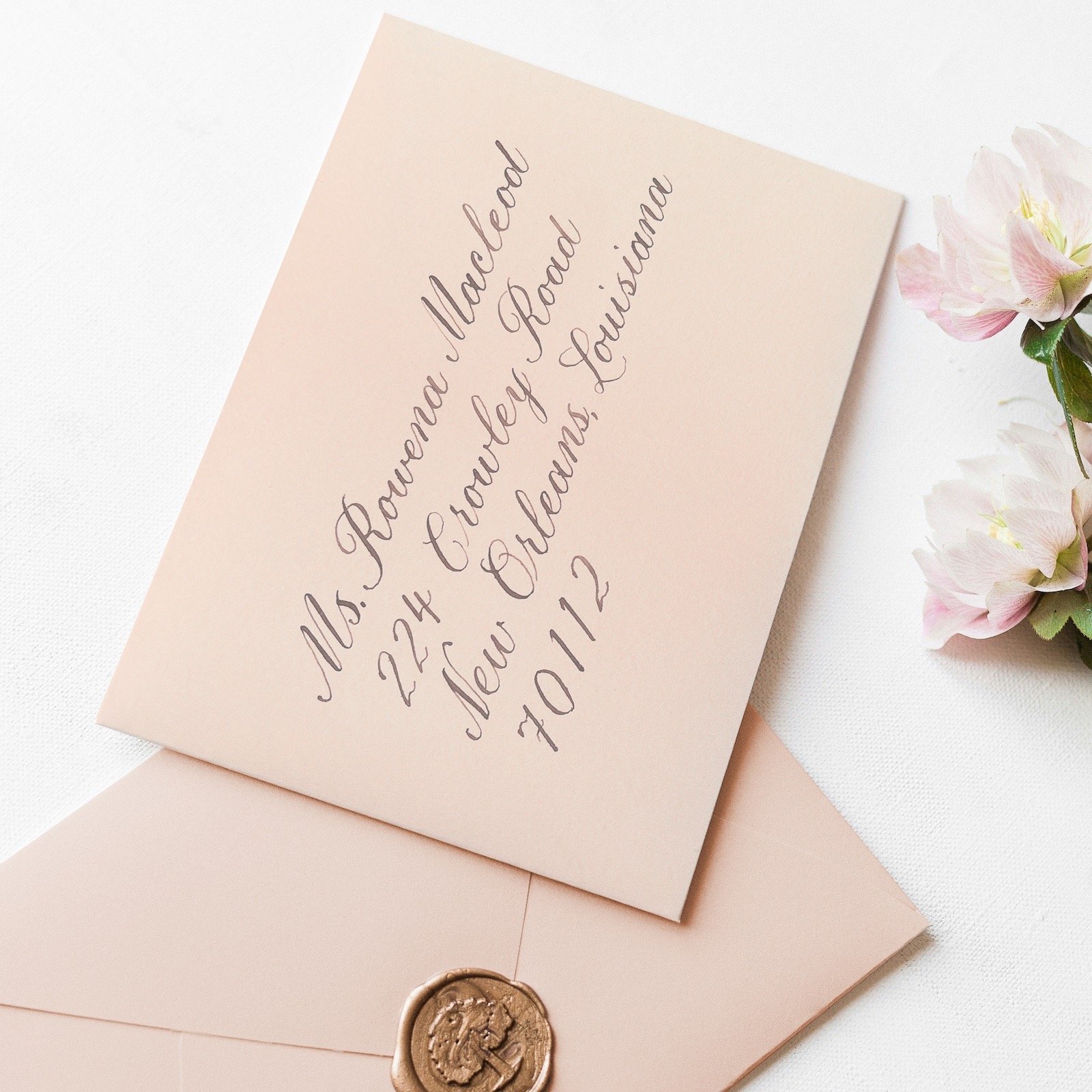 light pink envelope with an address written in calligraphy script in brown ink