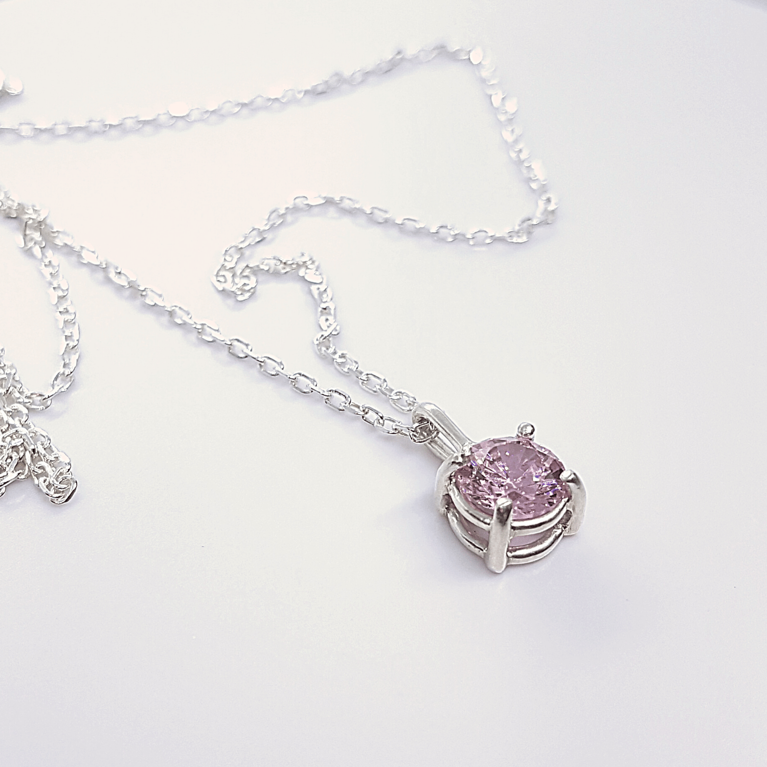 a necklace with a pink crystal pendant on a chain