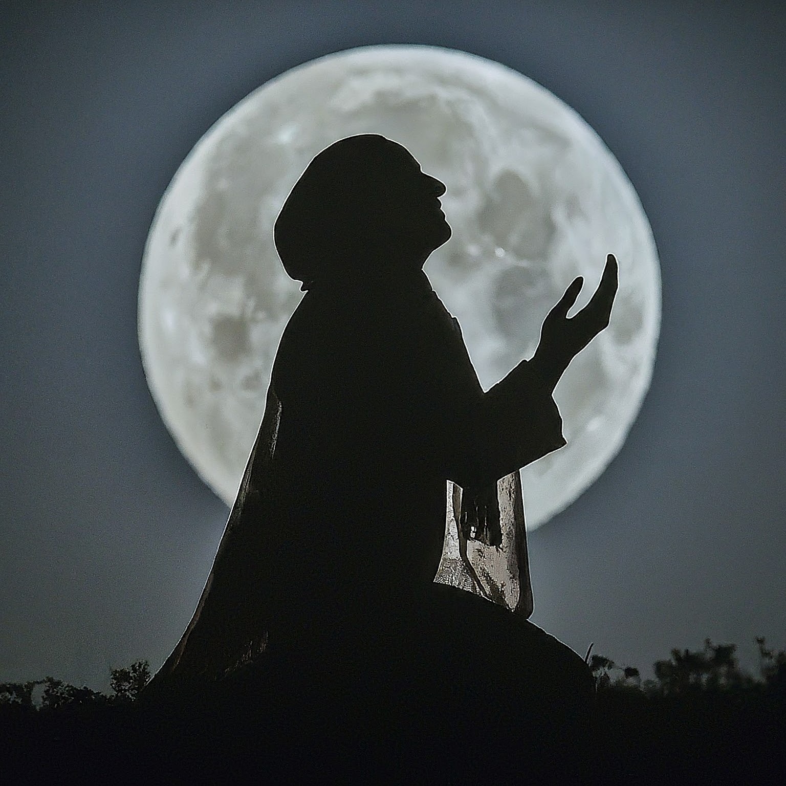a person praying in front of a full moon