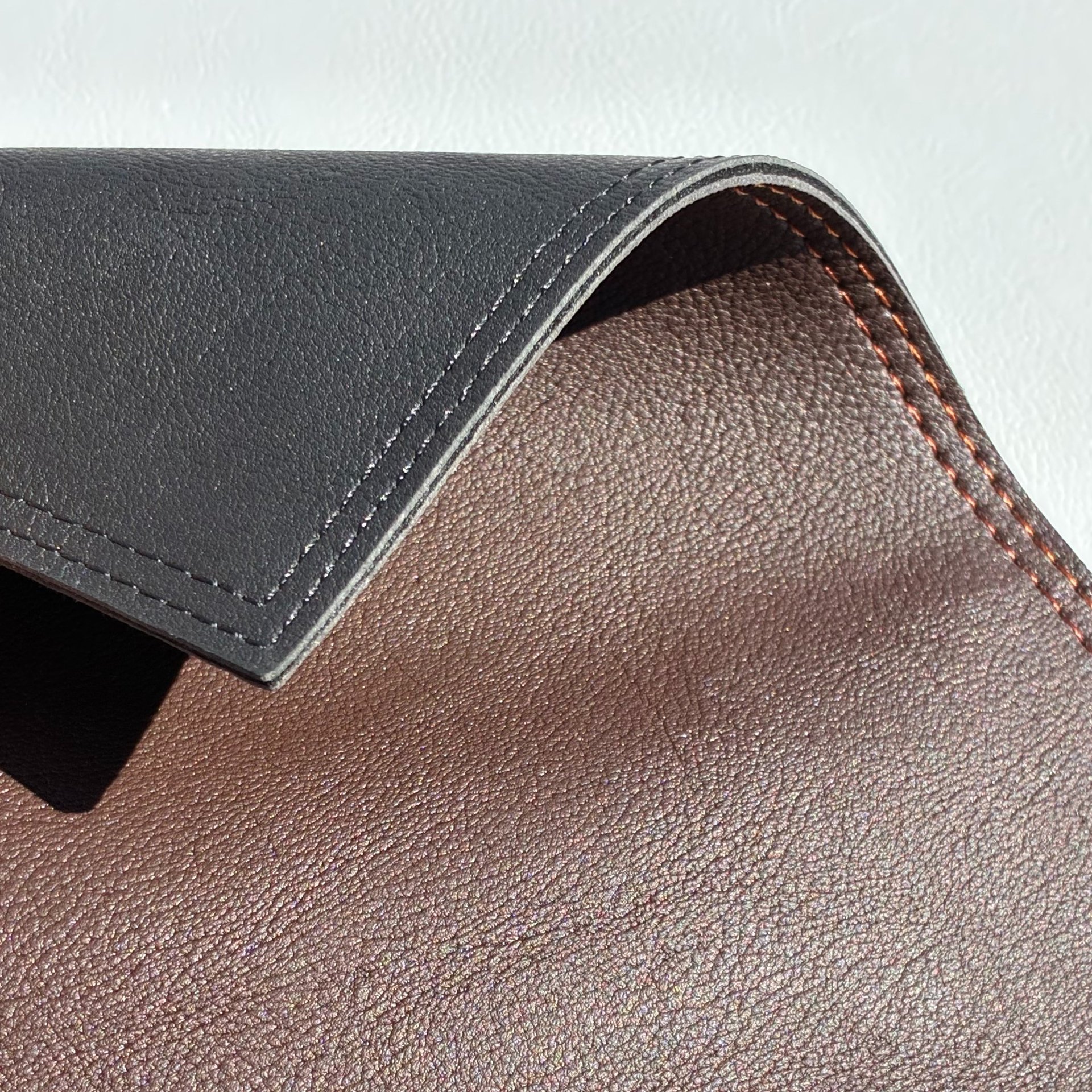 Detalle de un individual de similcuero graneado en color negro y marrón, con finas costuras