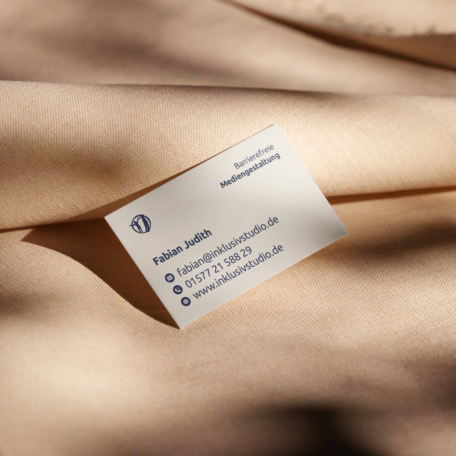 Visitenkarte von Fabian (inklusivstudio) mit Kontaktdaten liegt auf Leinentuch