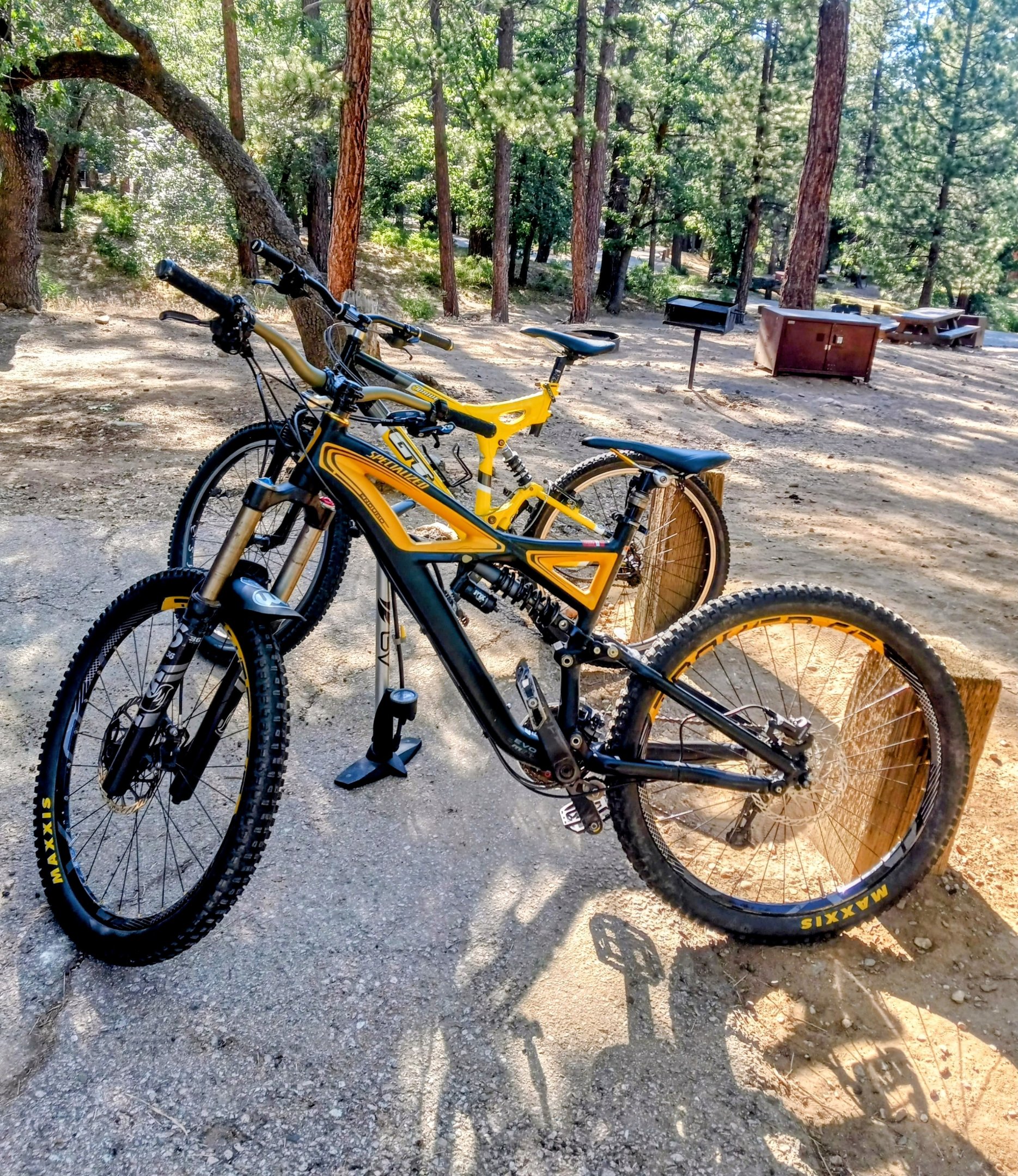 Two mountain bikes side by side on a trail showing handlebar width comparison