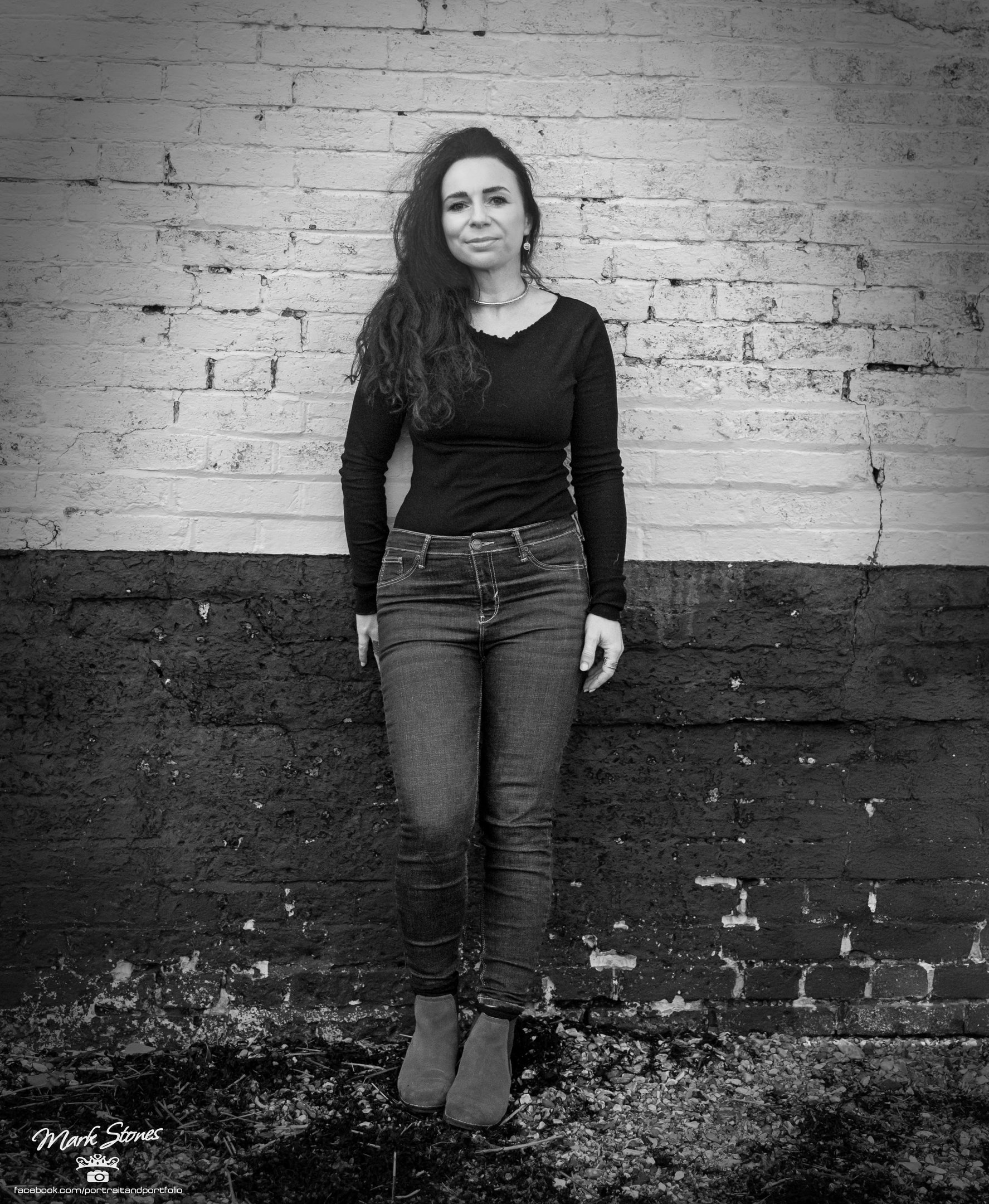 Black and white portrait of Helen Spooner, pianist and vocalist, standing against a brick wall.