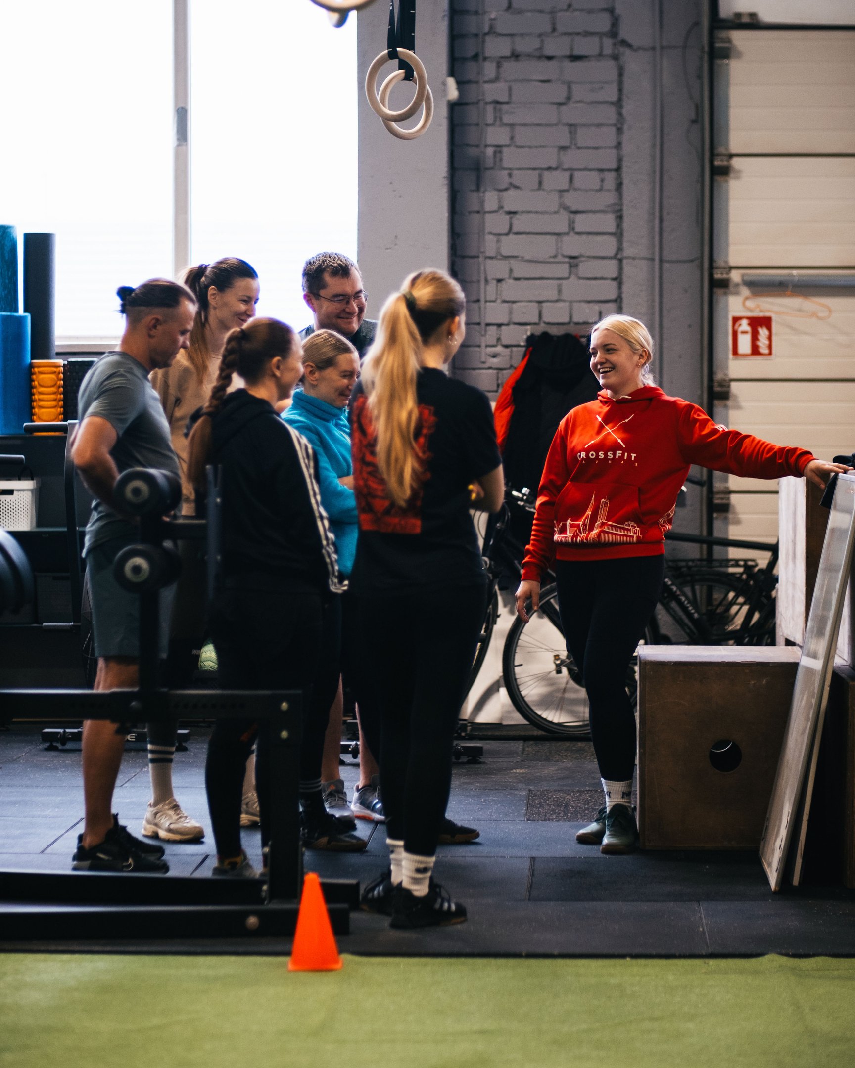 A diverse group of athletes talking to a female coach in a CrossFit gym during a fitness workout.