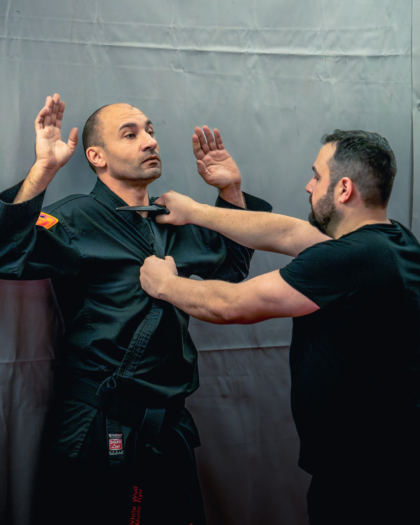 Self-defense instructor demonstrating a knife defense technique against a black belt martial artist.