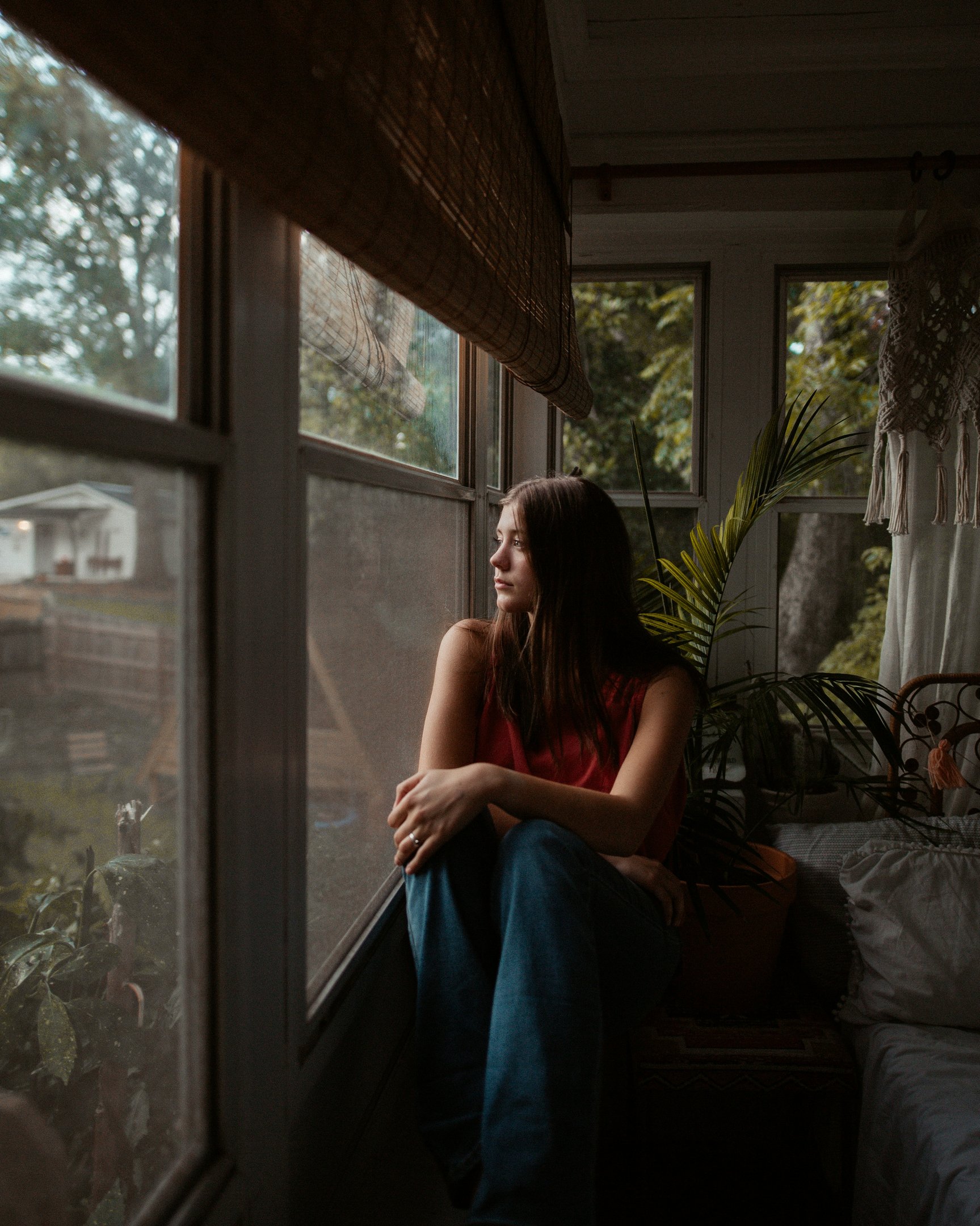Woman sitting quietly at a window, looking tired — signs of burnout