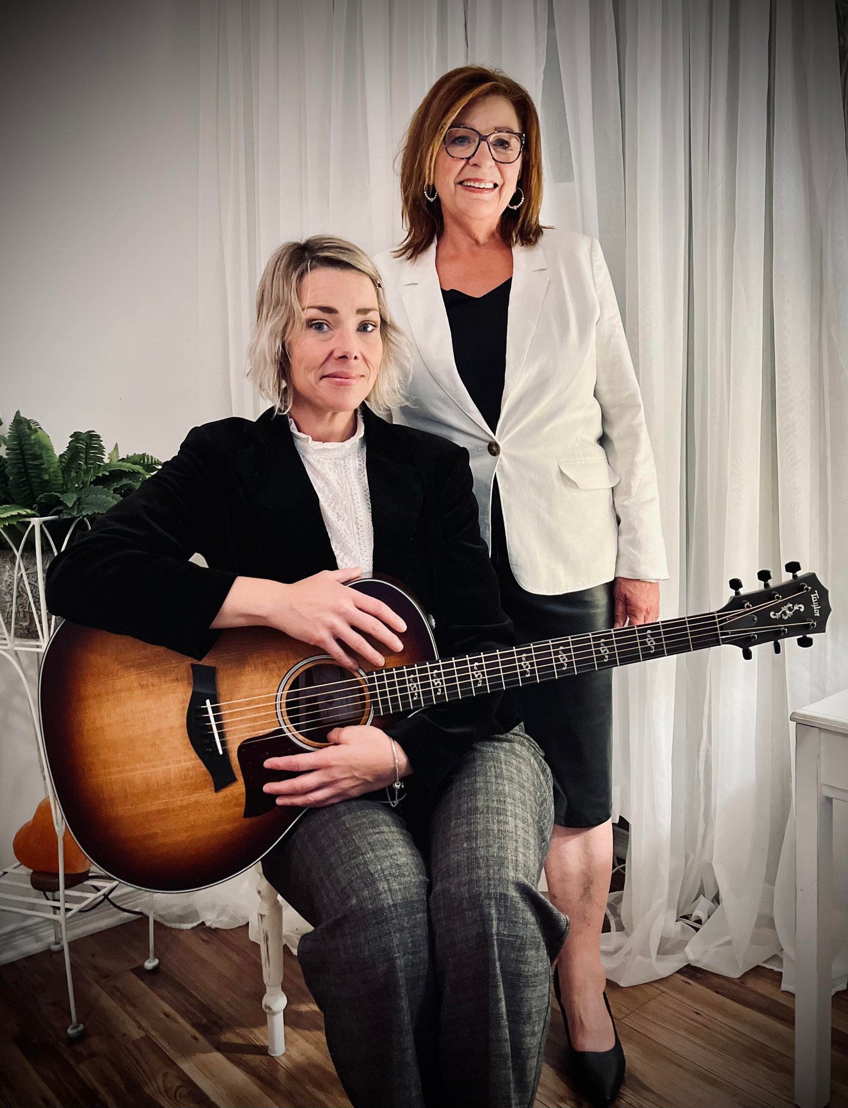 Colette et Caroline Lupien posent, l’une assise avec une guitare, l’autre debout, souriante. 